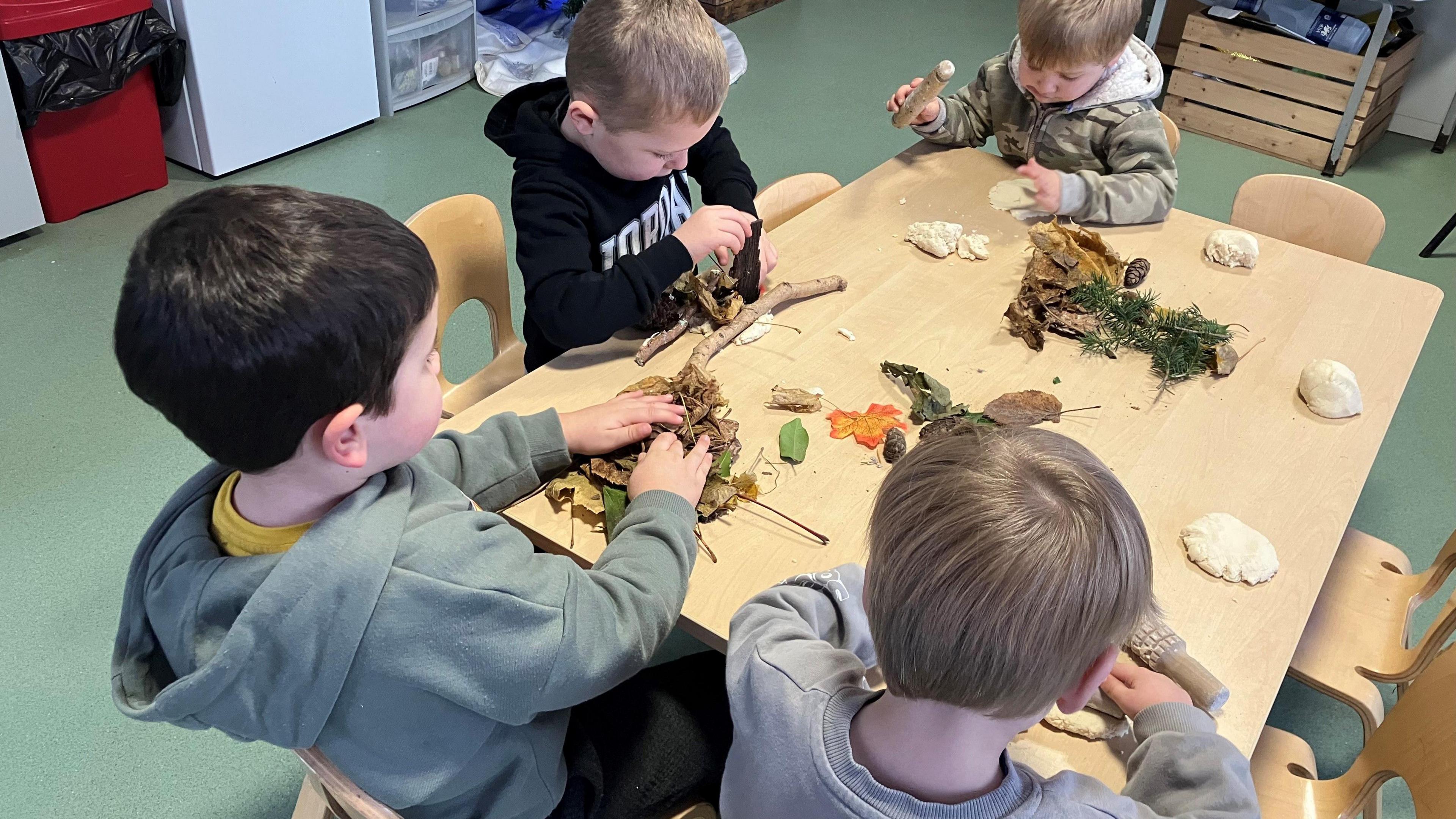 Small children working at a nature project on a table in a nursery