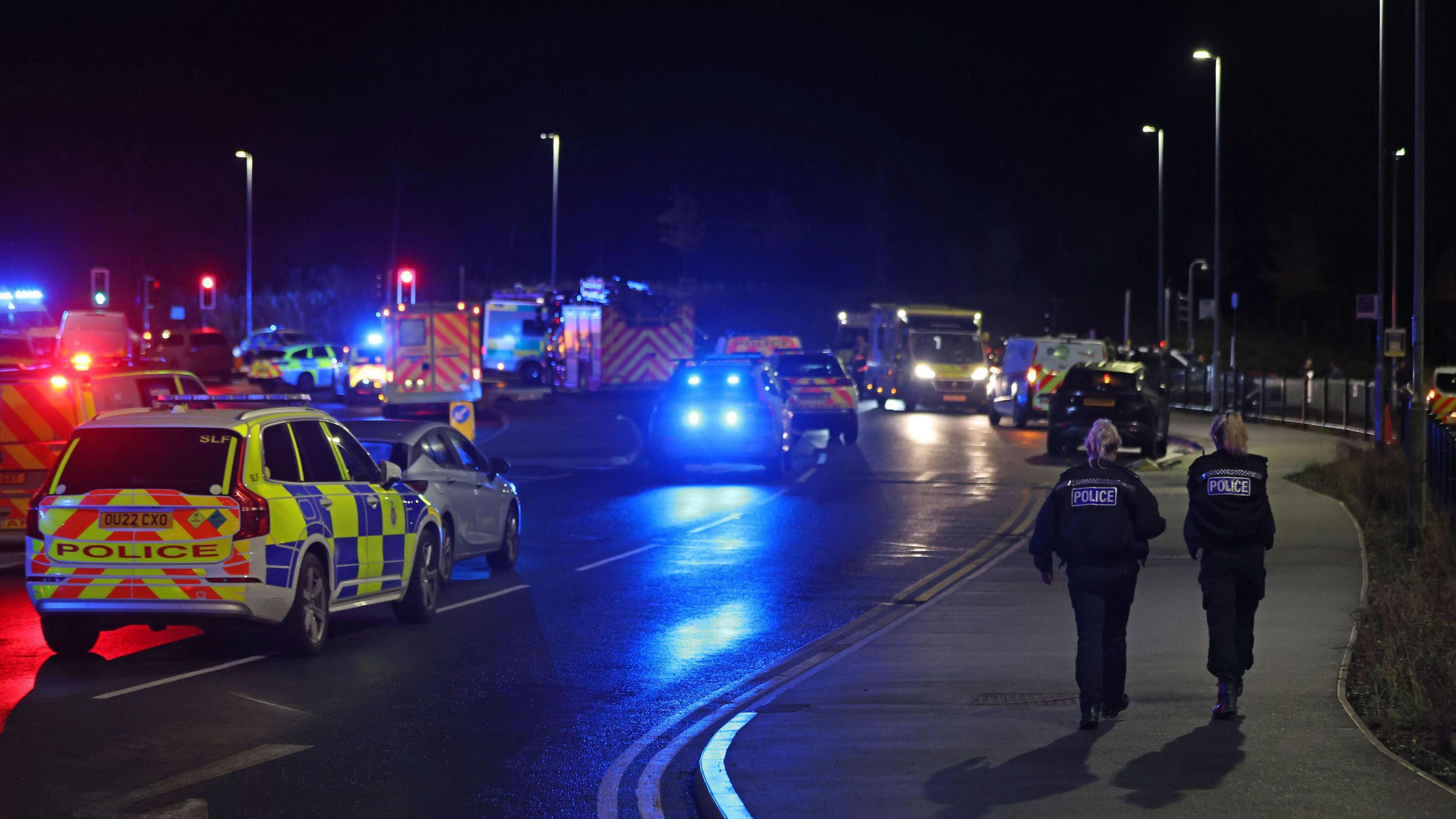 Emergency response including police cars and ambulances and police officers scene outside the train station.