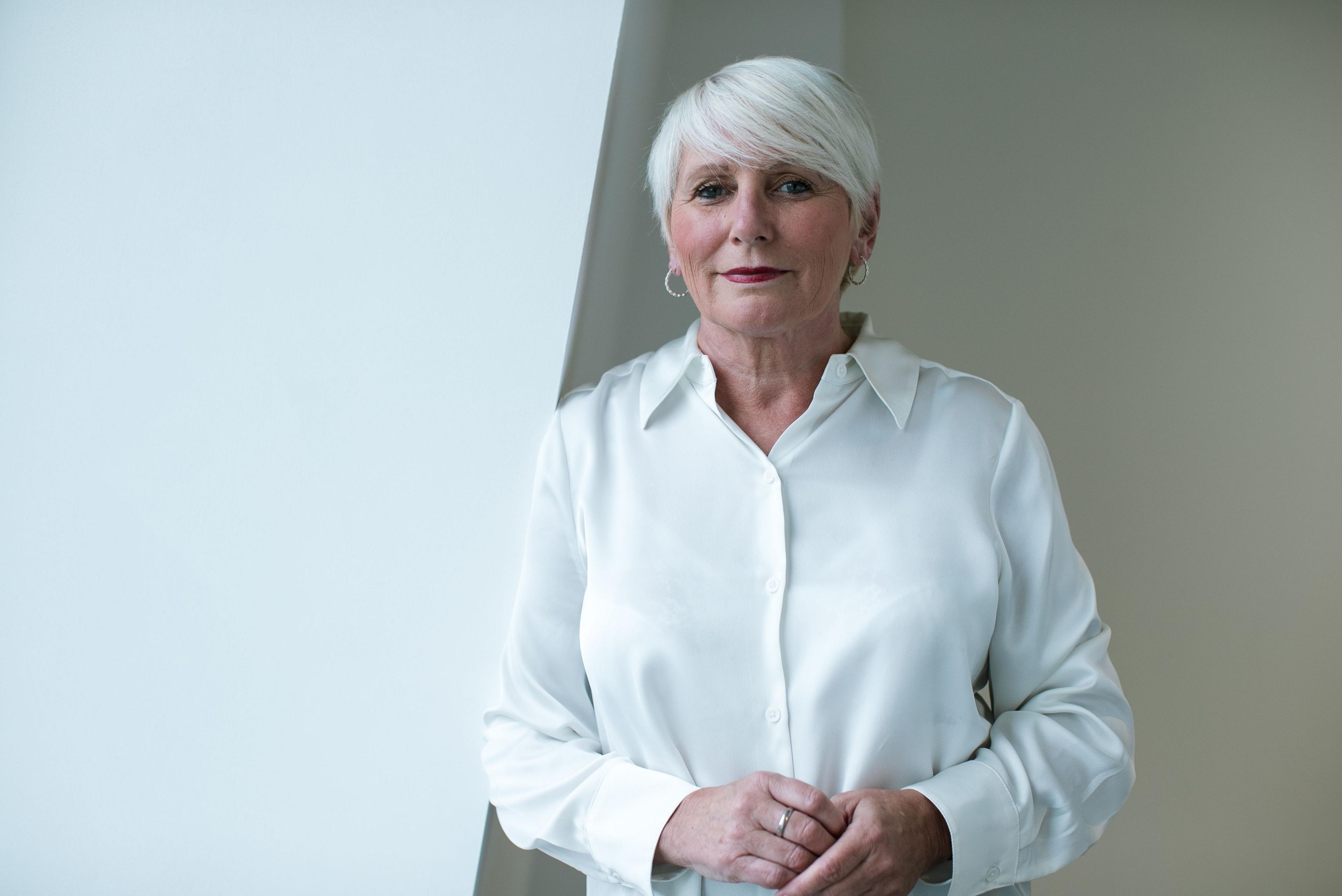 Louise Gilmour standing before a brown and white room