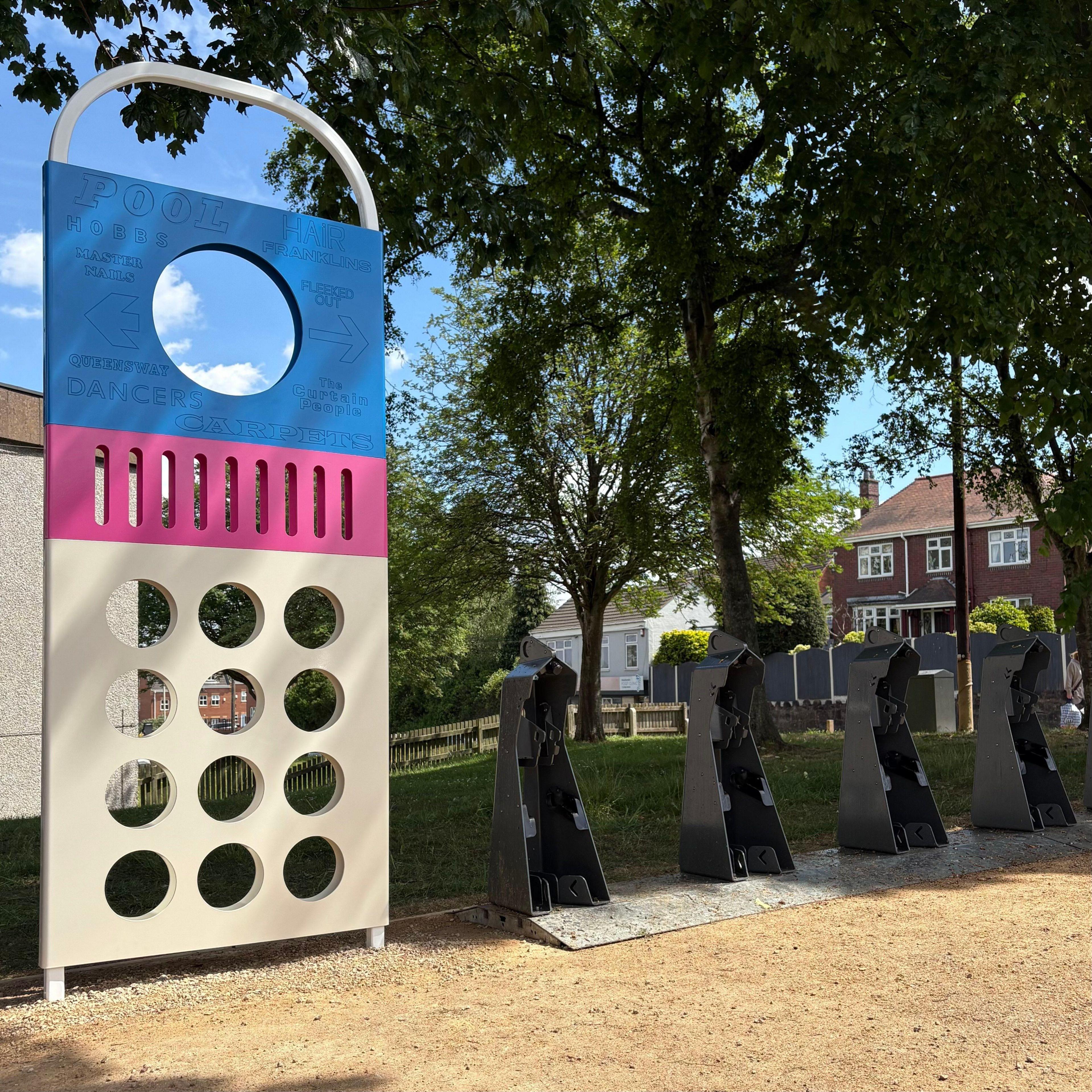 The blue, pink and white structure sits on a new green space next to bike hire hubs