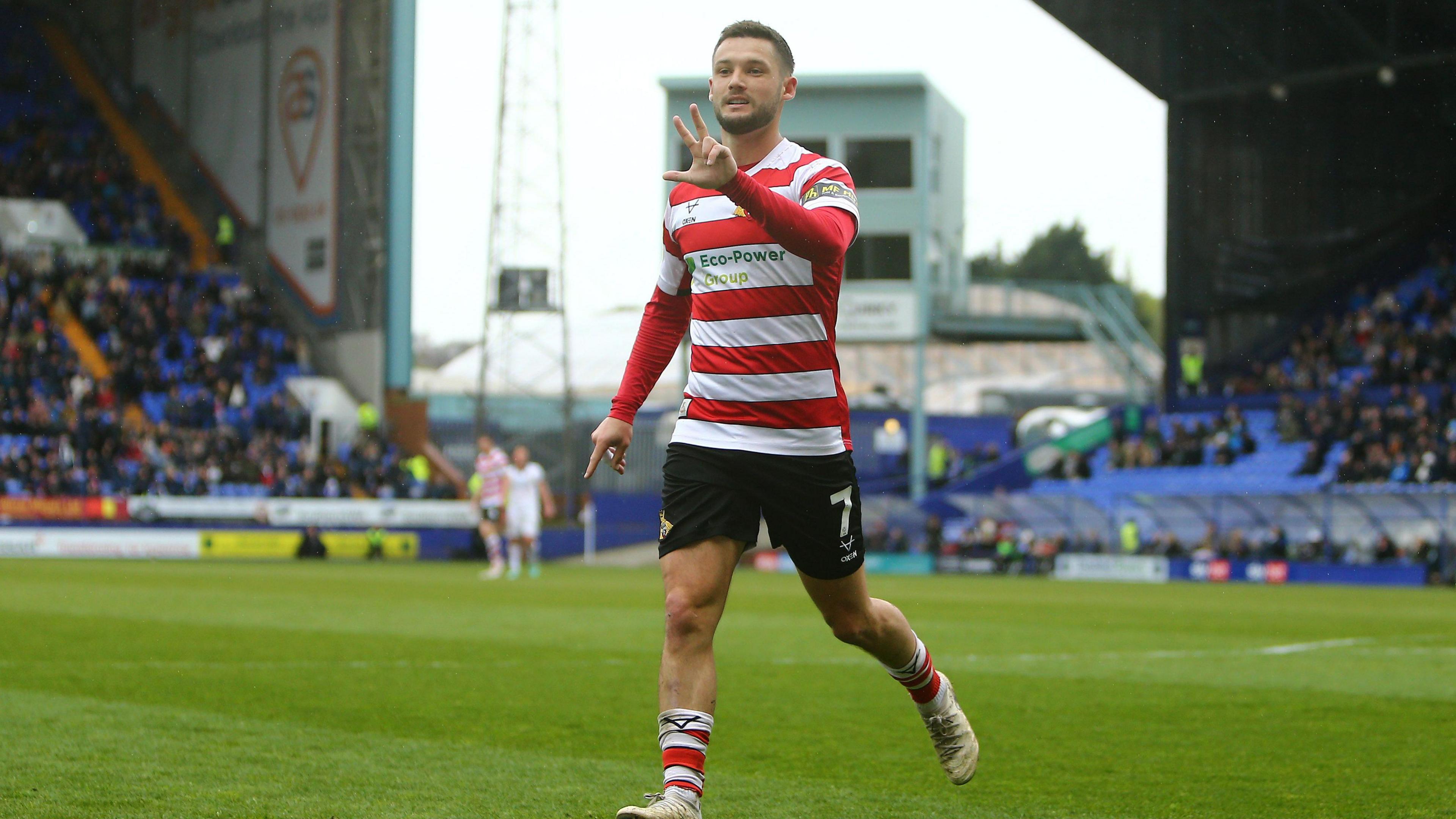 Doncaster forward holds three fingers up in celebration