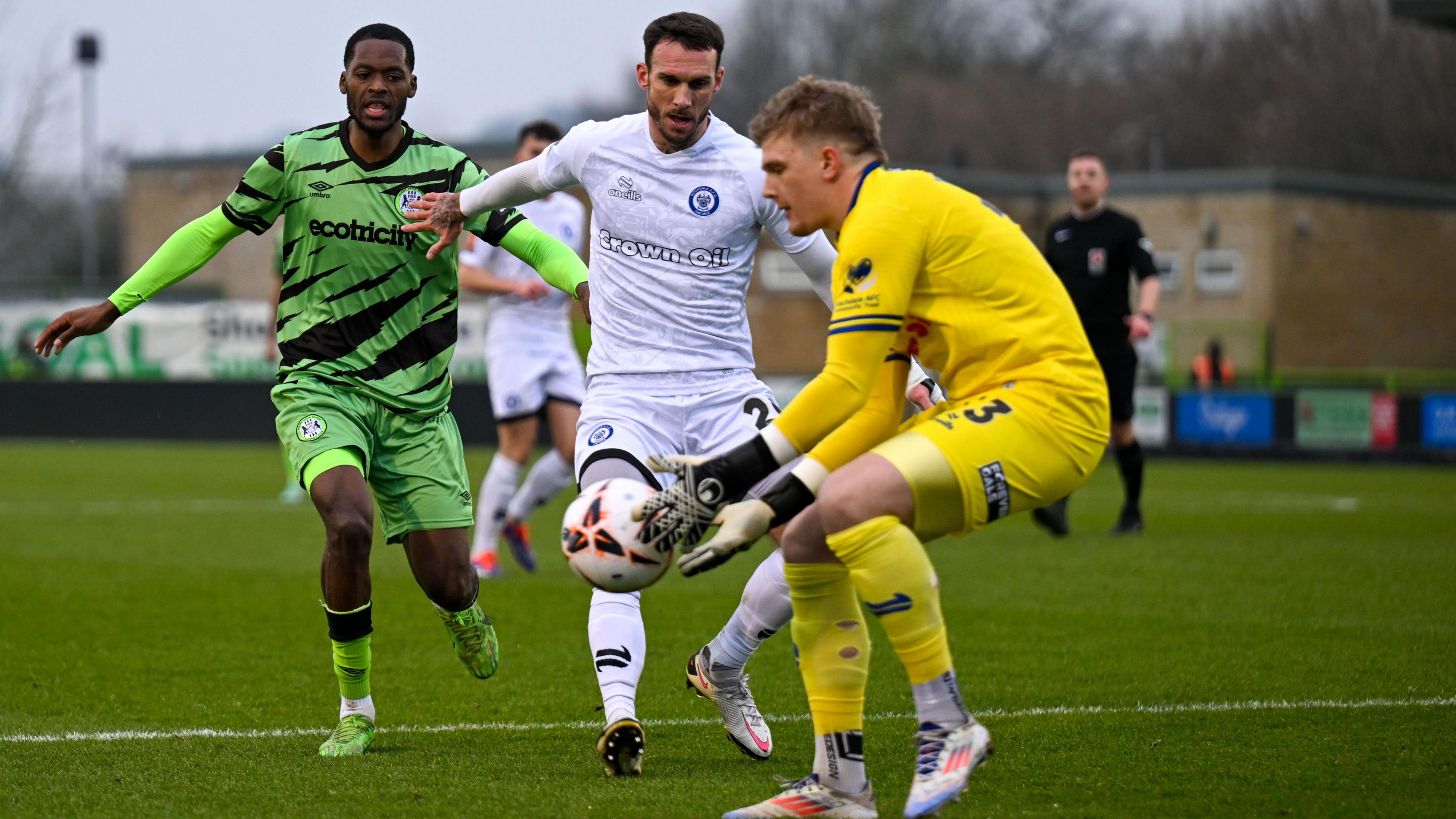 Sam Waller, in yellow, comes out of his goal to gather the ball under pressure from a Forest Green Rovers player during a match