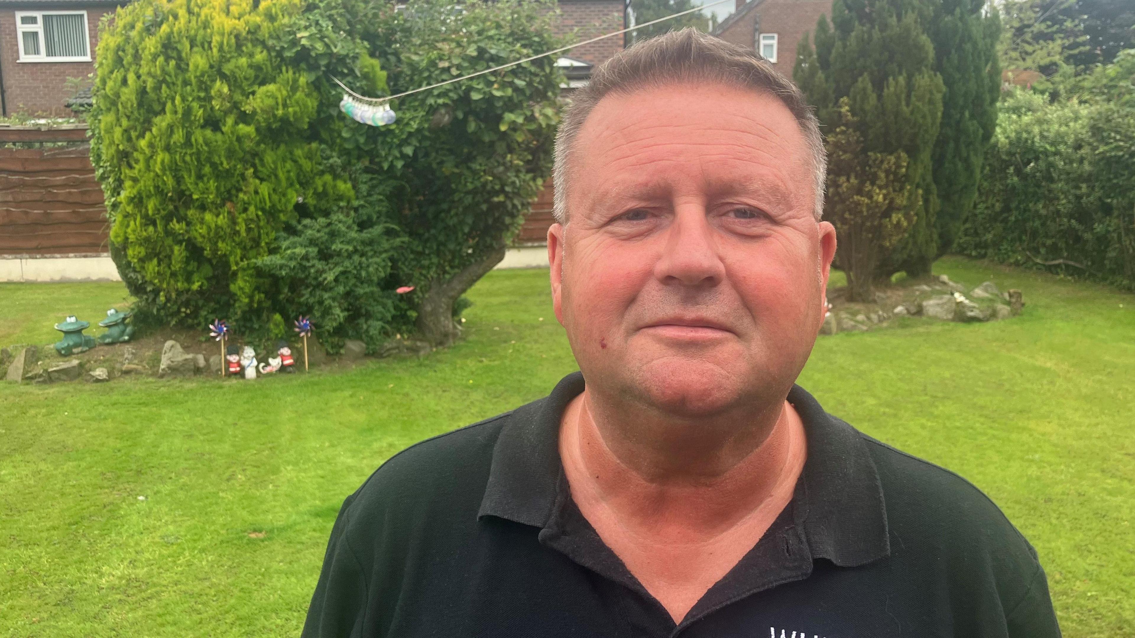 Photograph of John Cunningham, who worked at Manchester Airport in 1985 as an 18-year-old. He is pictured in the garden of his home in Wythenshawe, Greater Manchester.