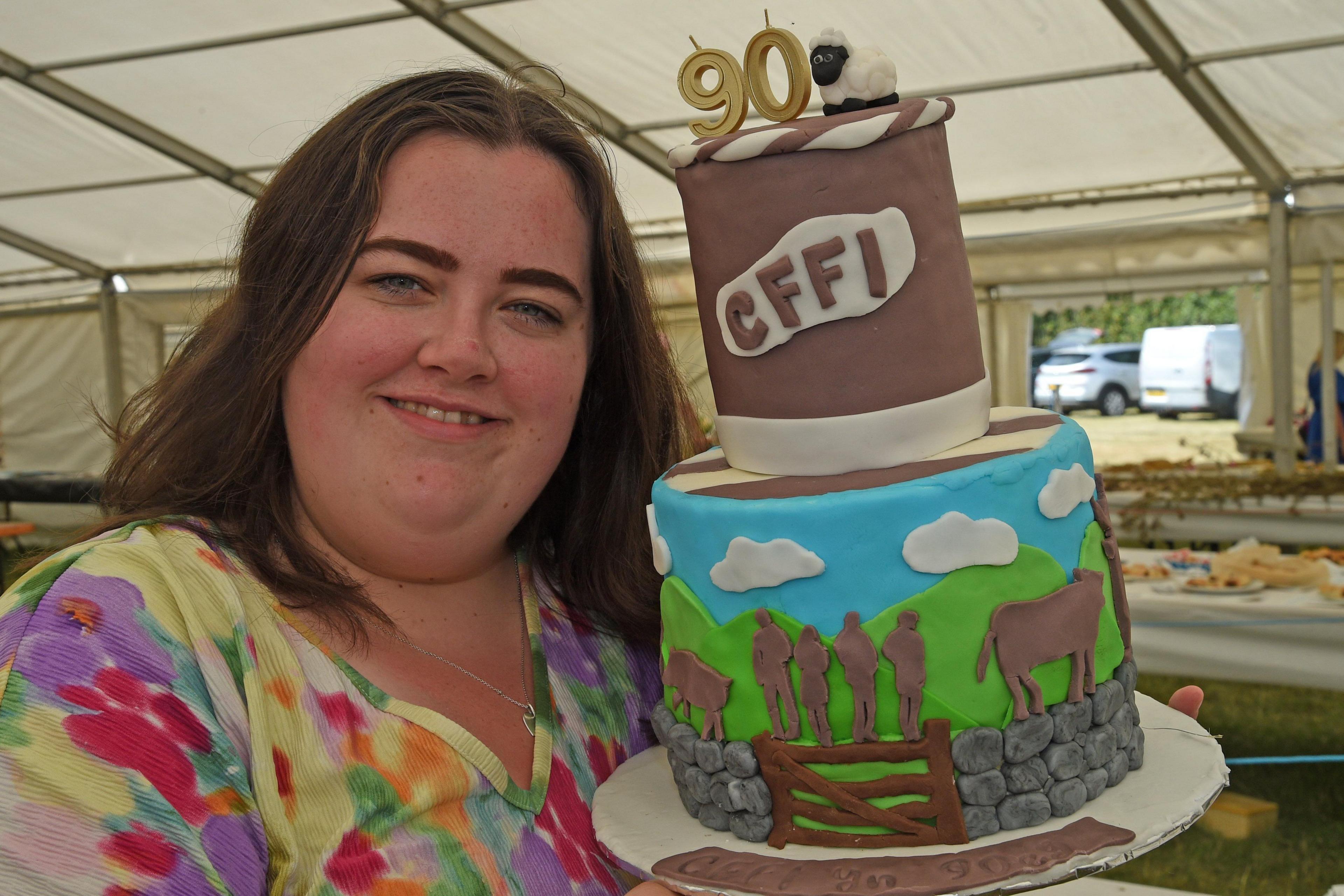 Lowri Hughes o Fryngwran gyda'i chacen a ddaeth i'r brig yn y gystadleuaeth adddurno cacen i ddathlu 90 mlynedd o fodolaeth Mudiad Ffermwyr Ifanc Cymru
