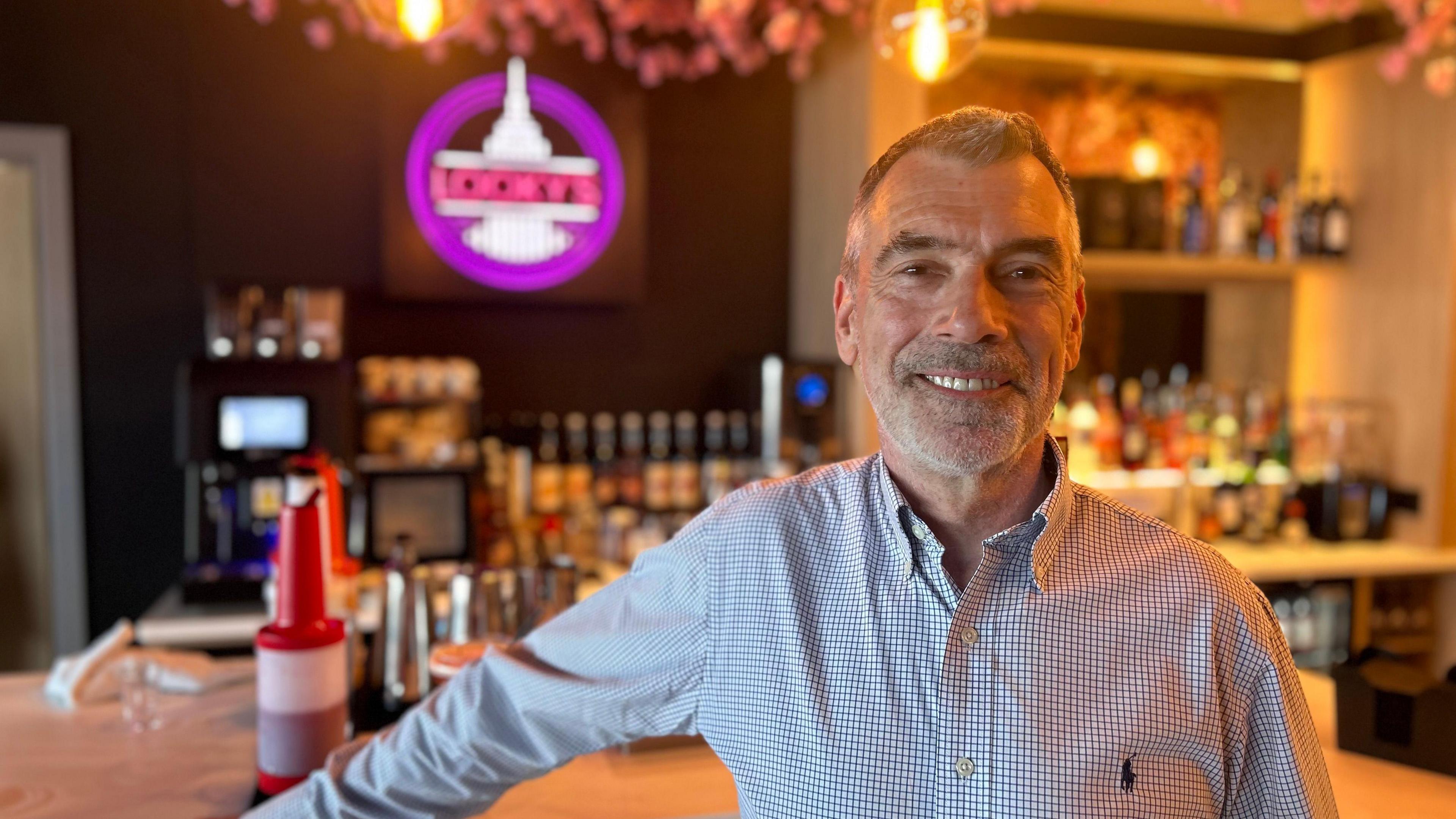 A closeup of a man smiling in a modern-looking bar