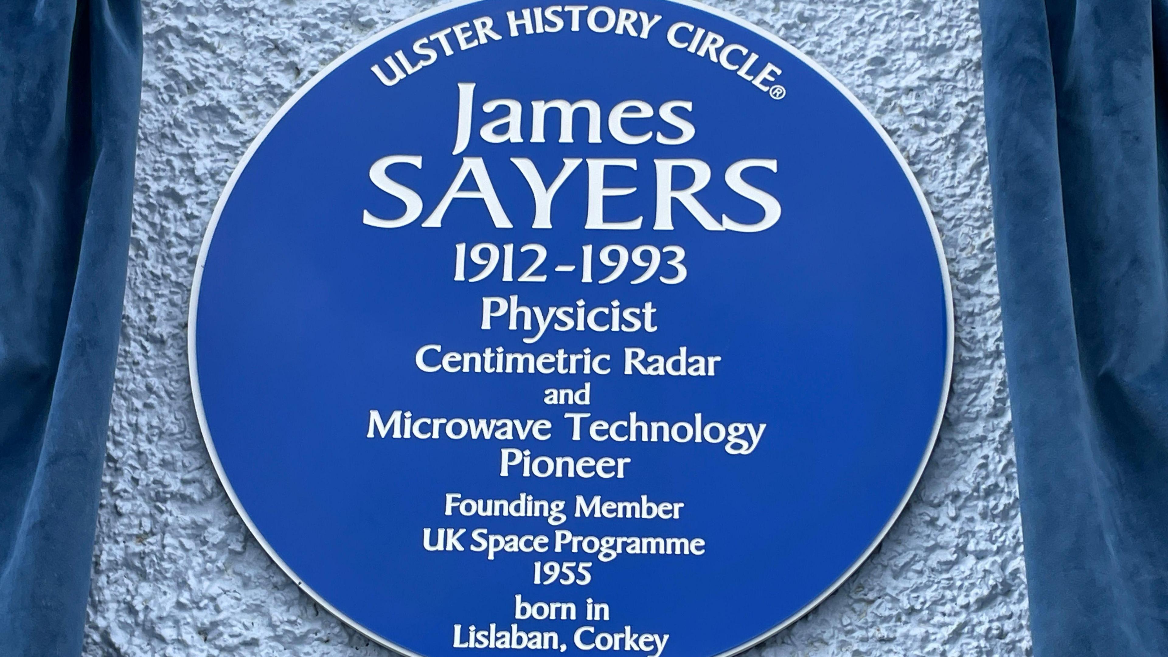 Blue plaque for James Sayers. It reads 'Ulster History Circle - James Sayers - 1912-1993 - Physicist - Centimetric Radar and Microwave Technology Pioneer - Founding Member UK Space Programme - 1955 born in Lislaban, Corkey'