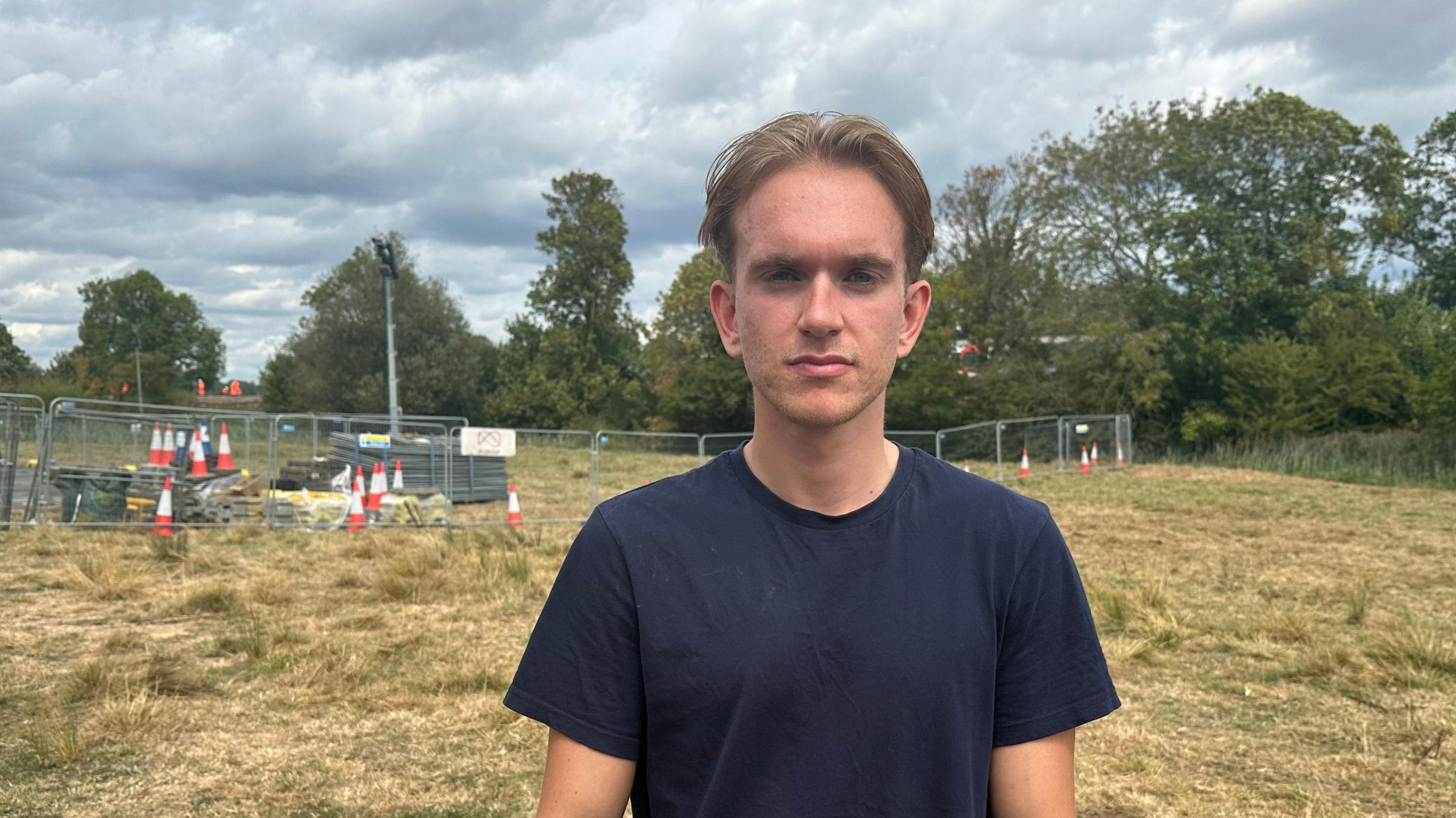 A student wearing a navy blue t-shirt stood near a cordon in a field.