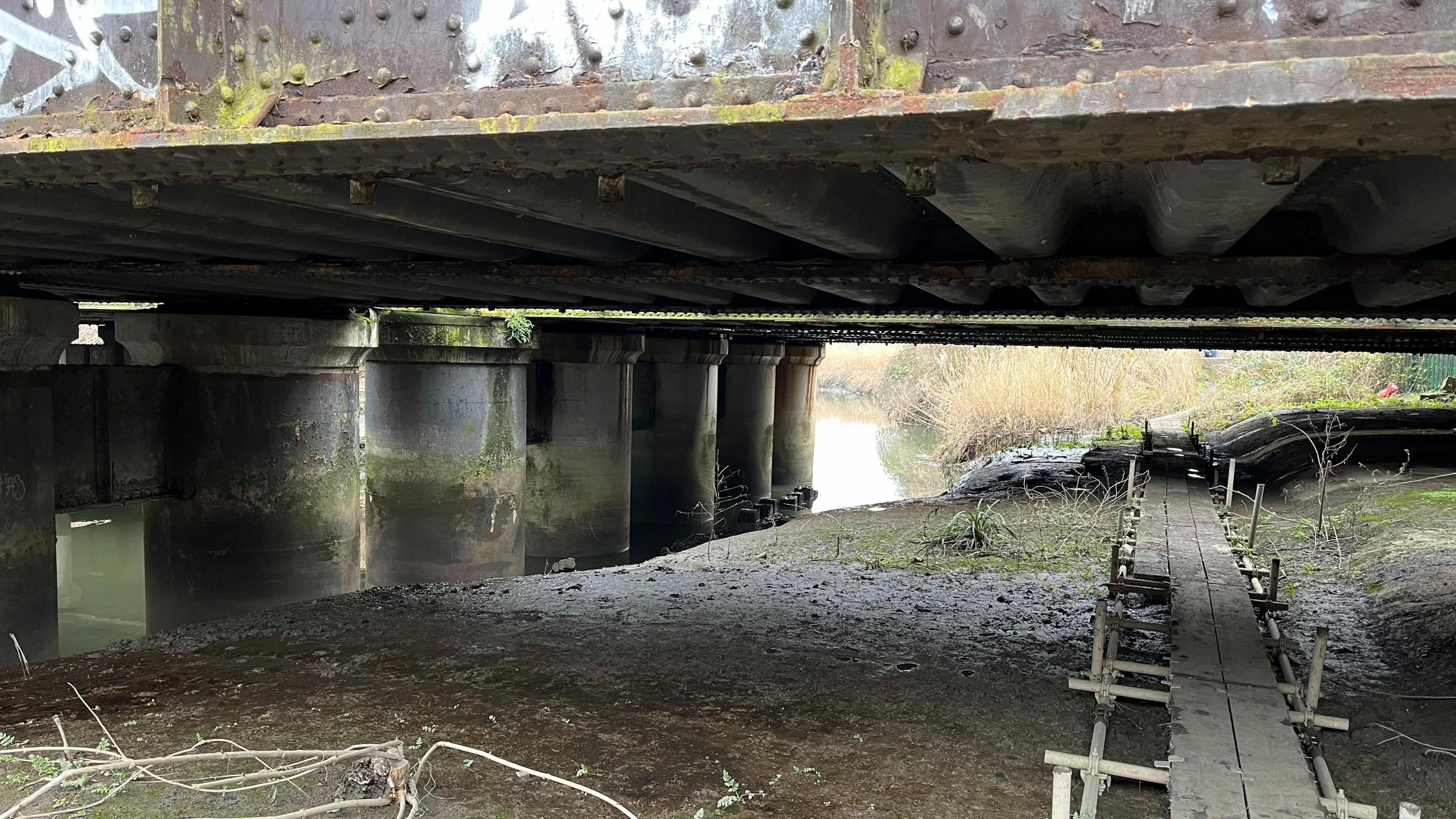 A bridge passes over a river. There is a walkway over mudflats.