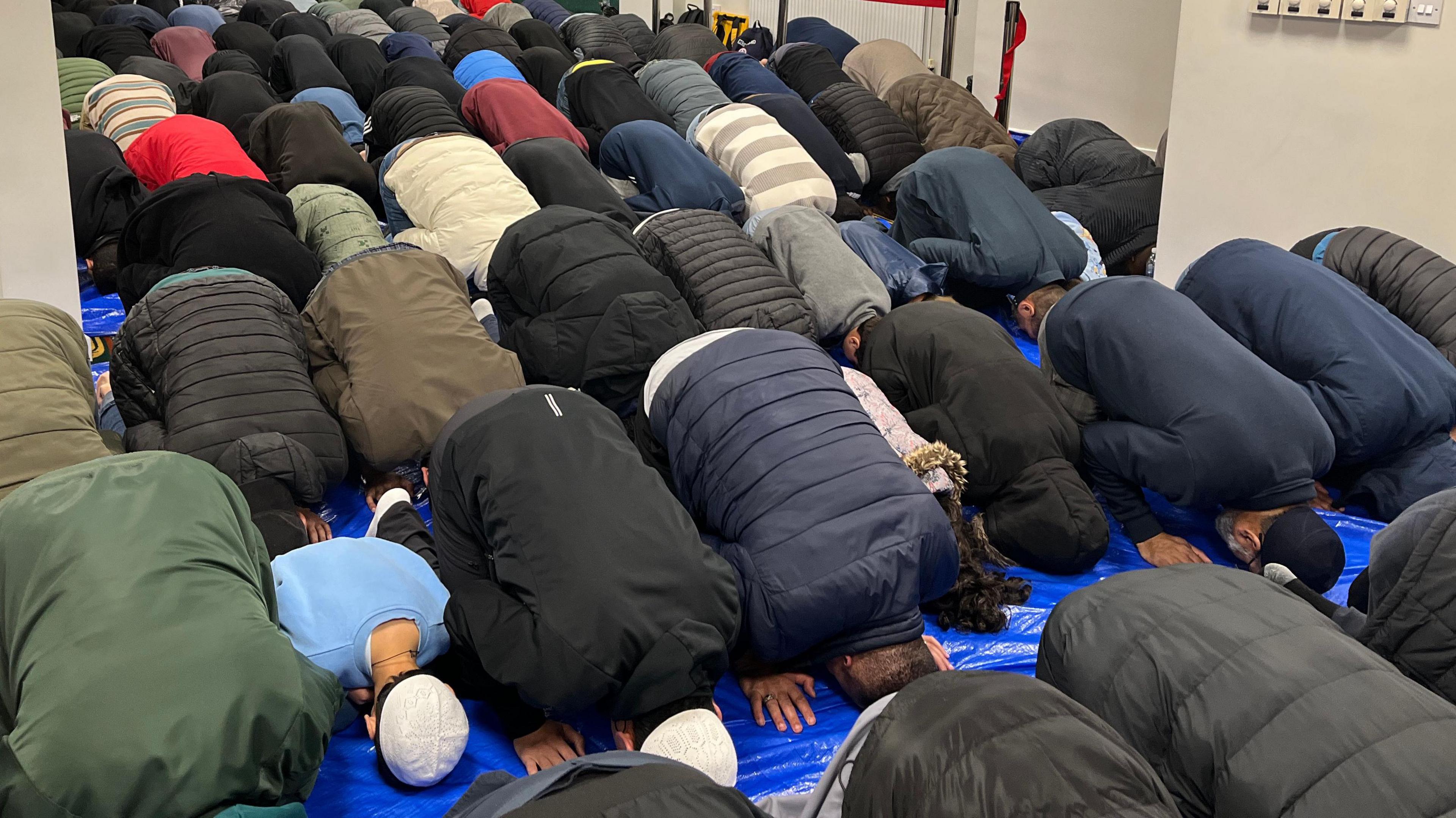 A room full of people kneeling on the floor with their heads bowed down in prayer