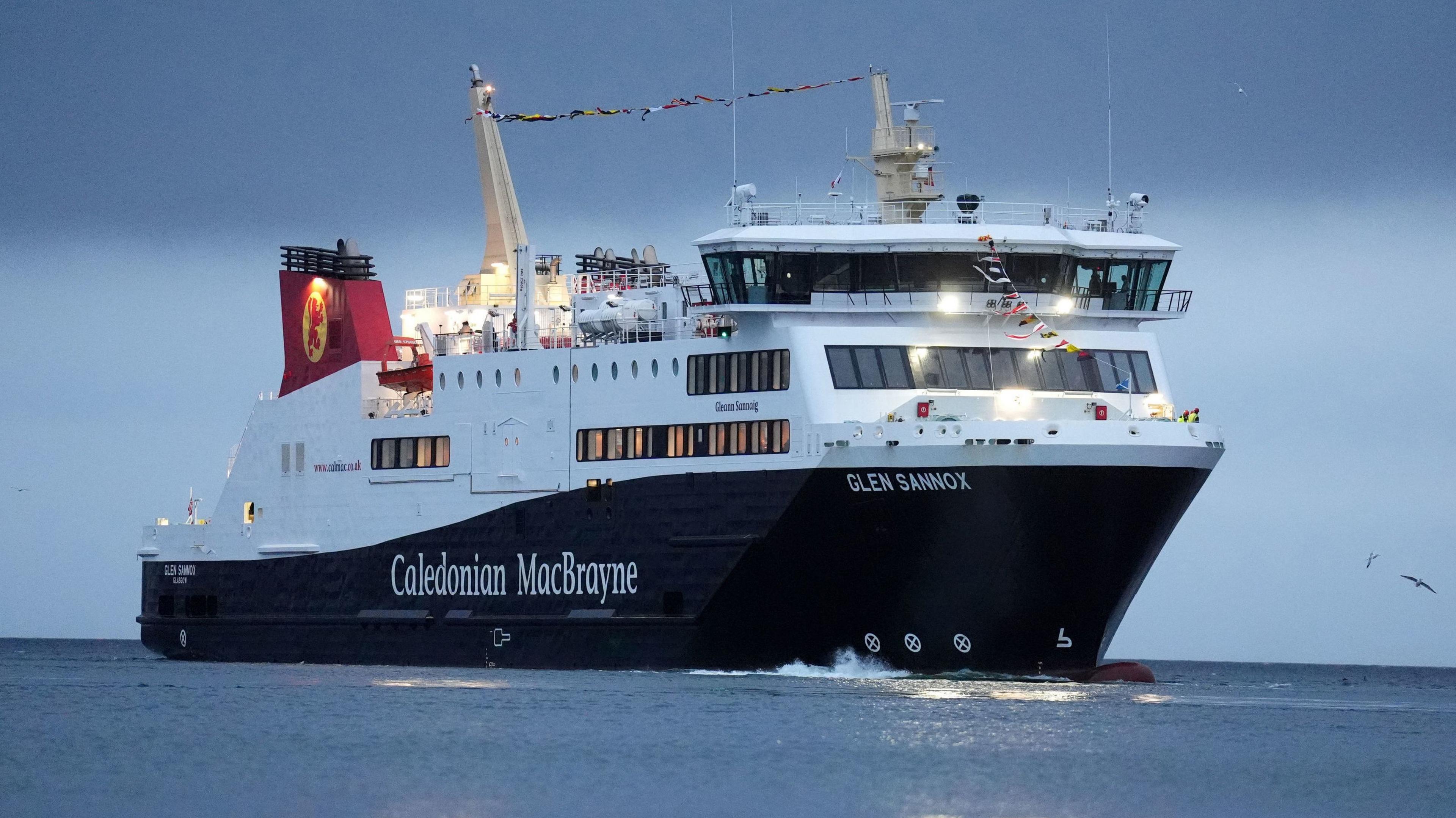 A black and white ship with red funnels in the early morning light