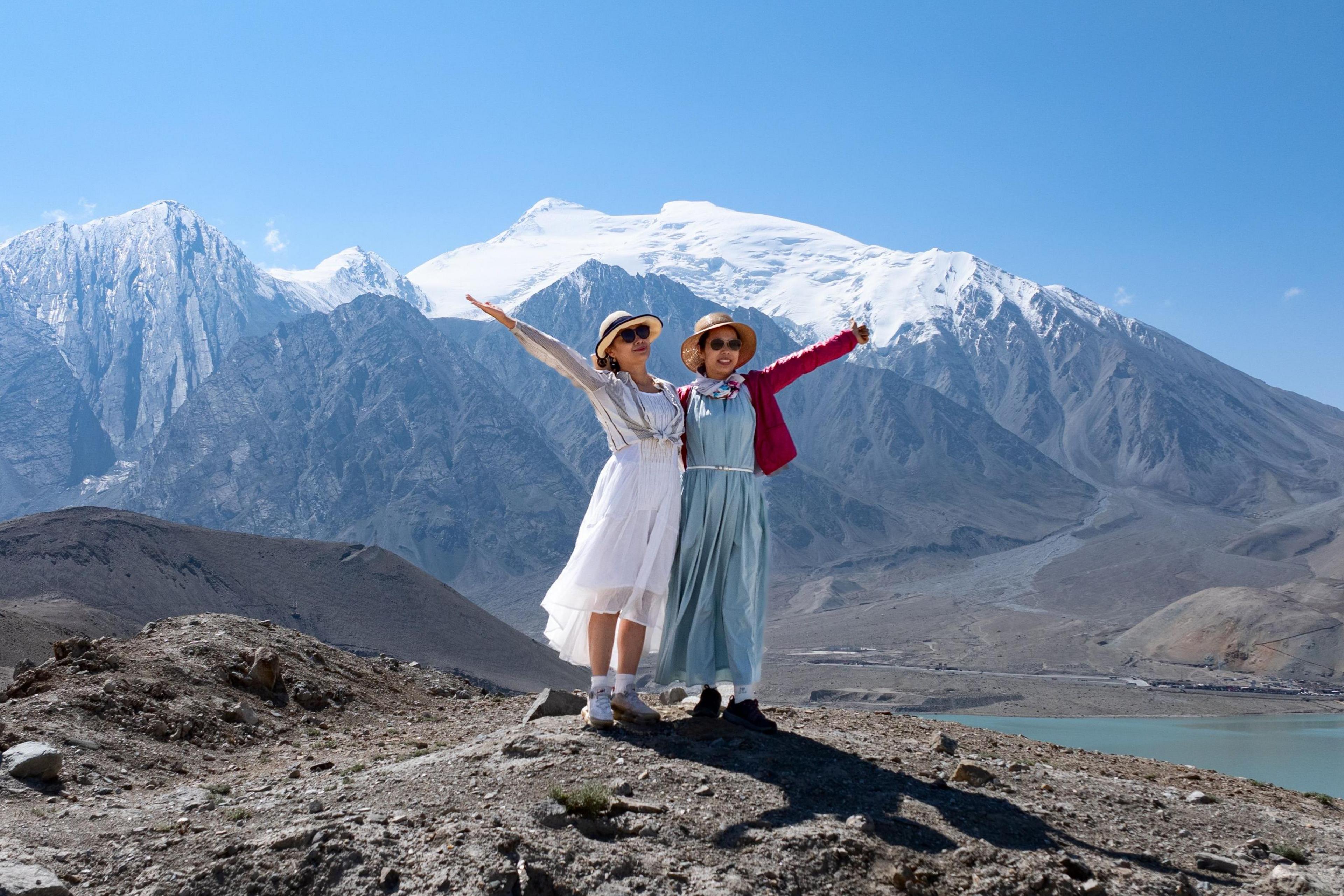 Two women posing for a picture at White Sand Lake in Xinjiang's Akto County