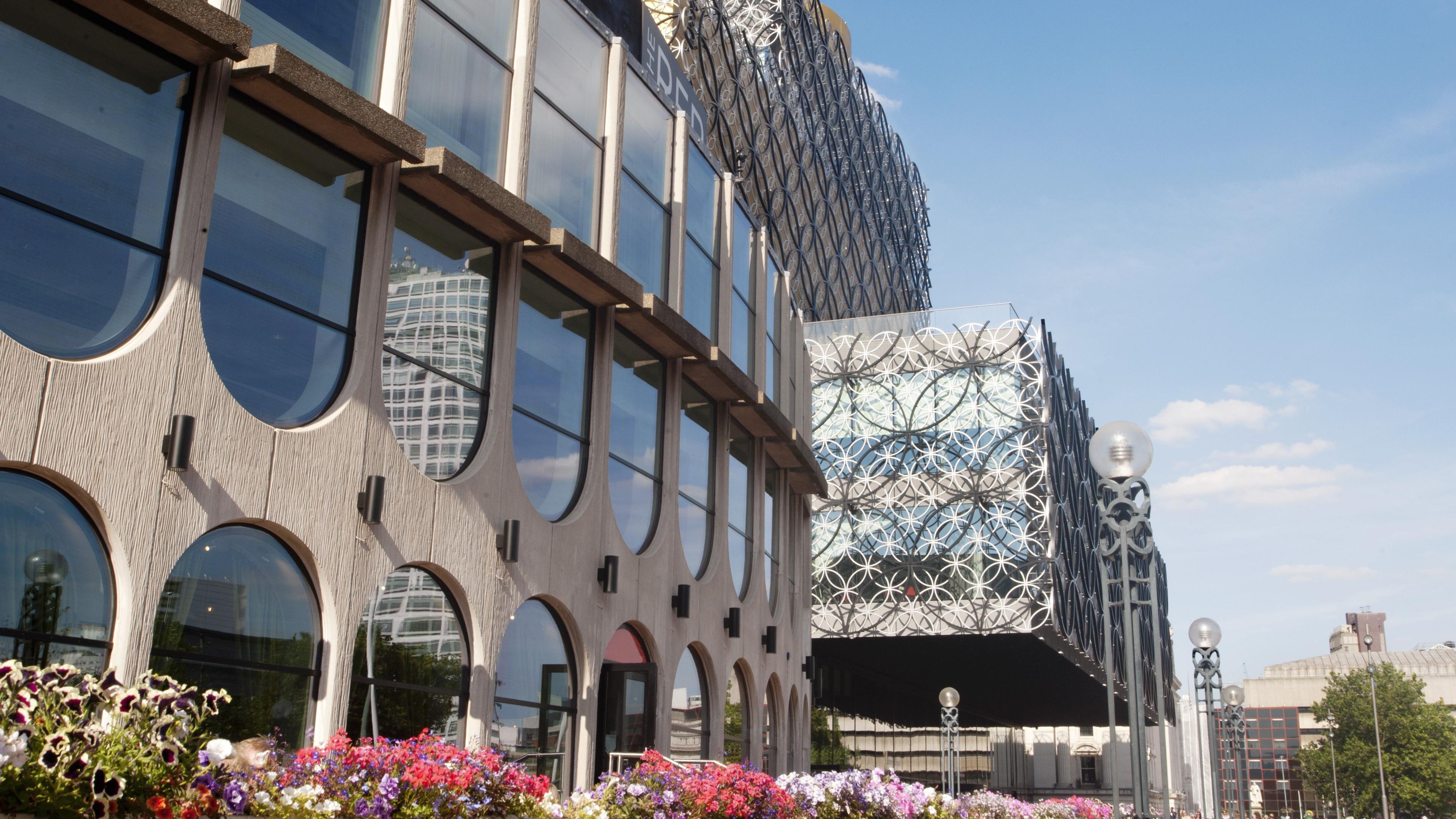 The front facade & cafe area of Birmingham Rep in Centenary Square, with the Library of Birmingham seen just behind