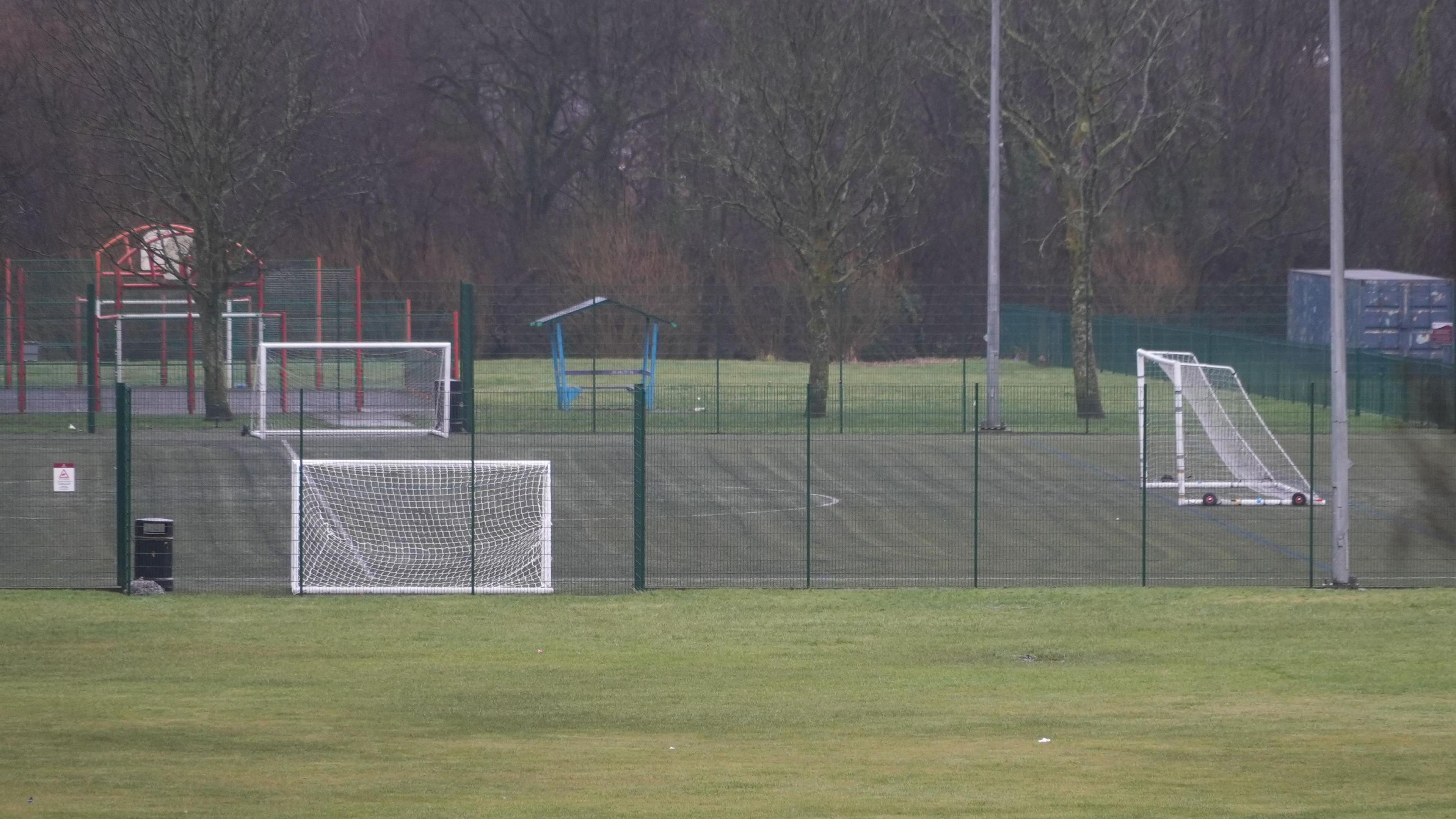 Football pitch, with white goals and a green cage fencing around it