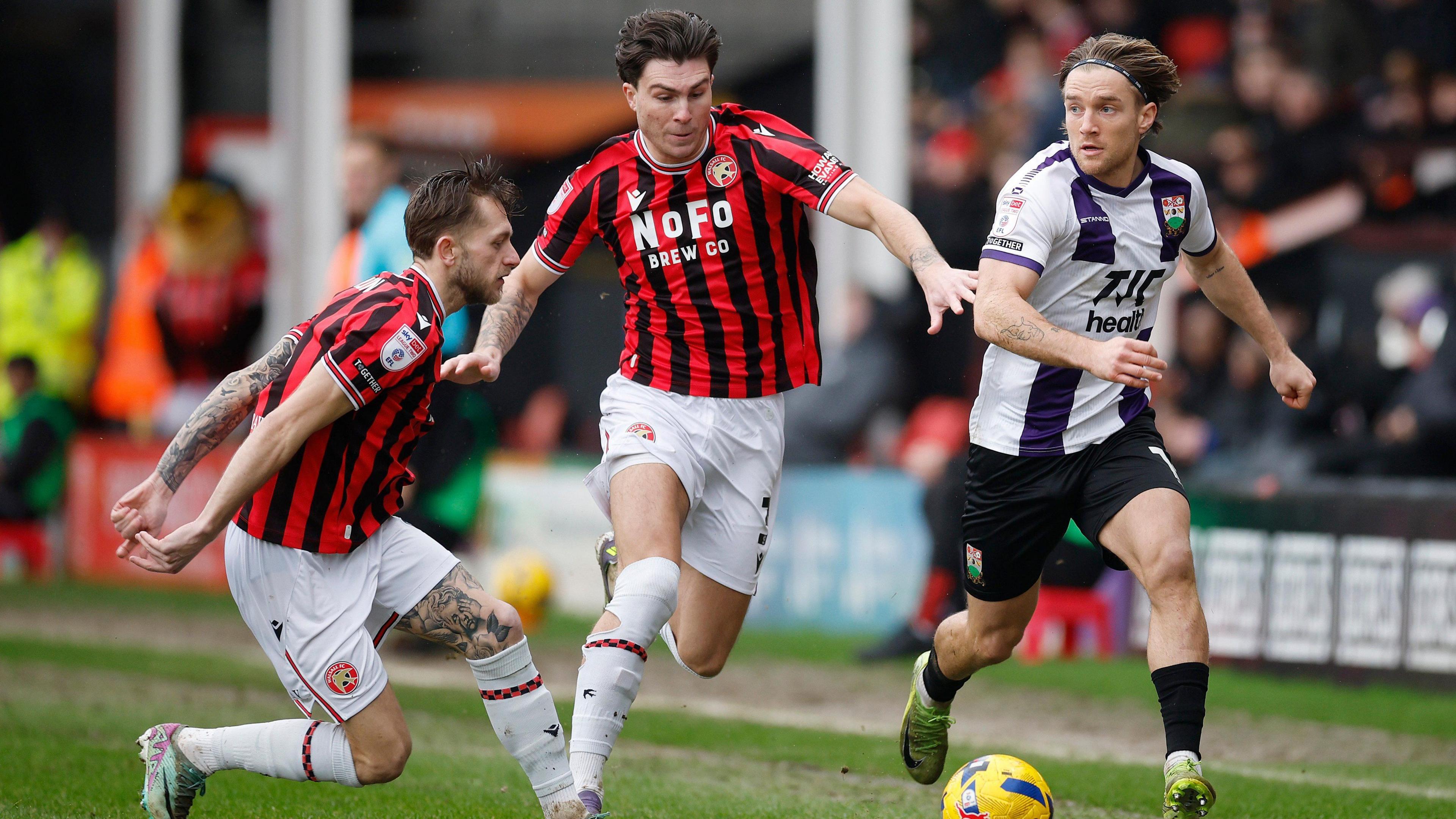 Mason Hancock in the centre of the picture competes to win the ball during a match for Walsall