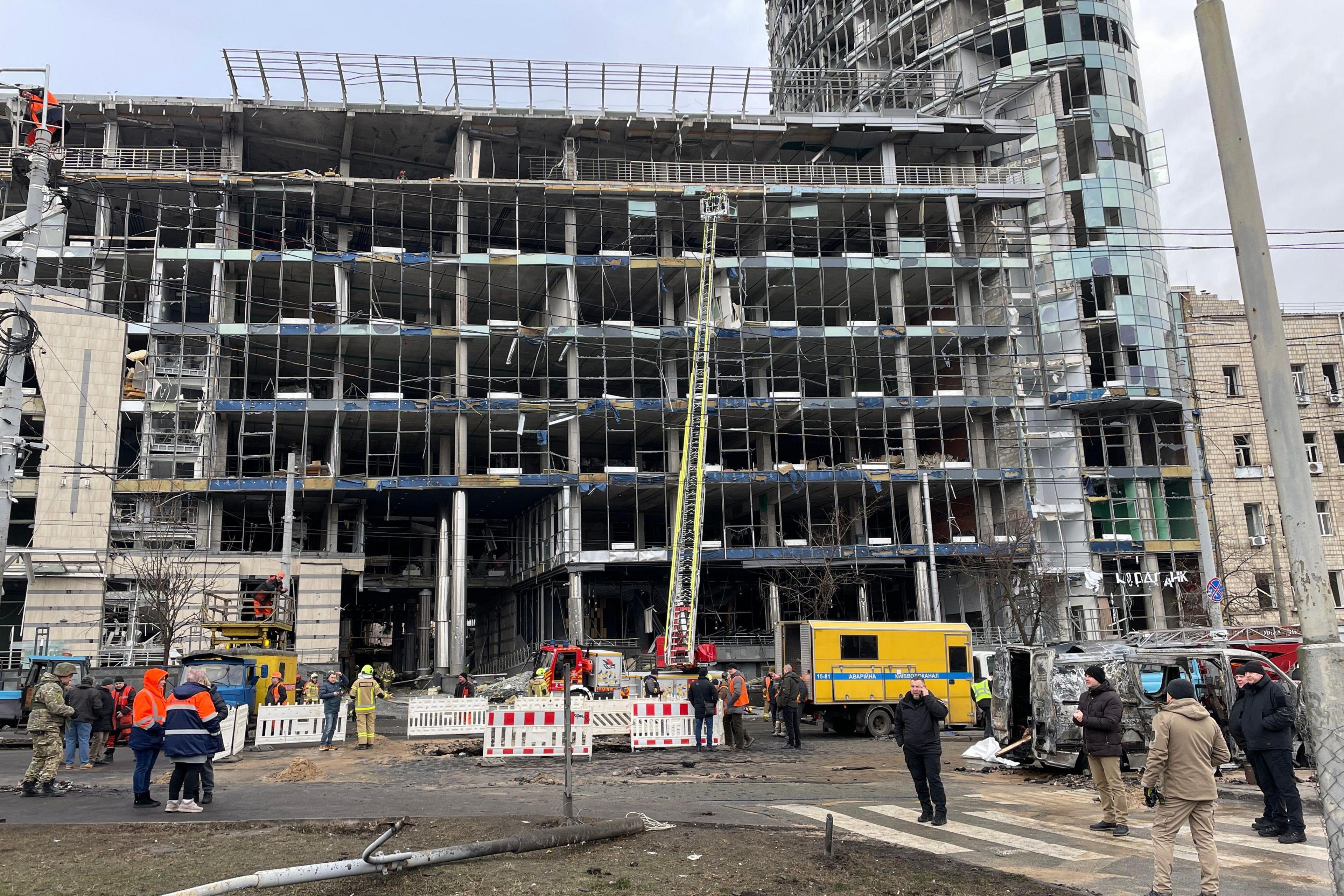 The damage to the business centre in Kyiv. A crane can be seen inspecting the building, which has glass blown out. Emergency responders stand around the site.