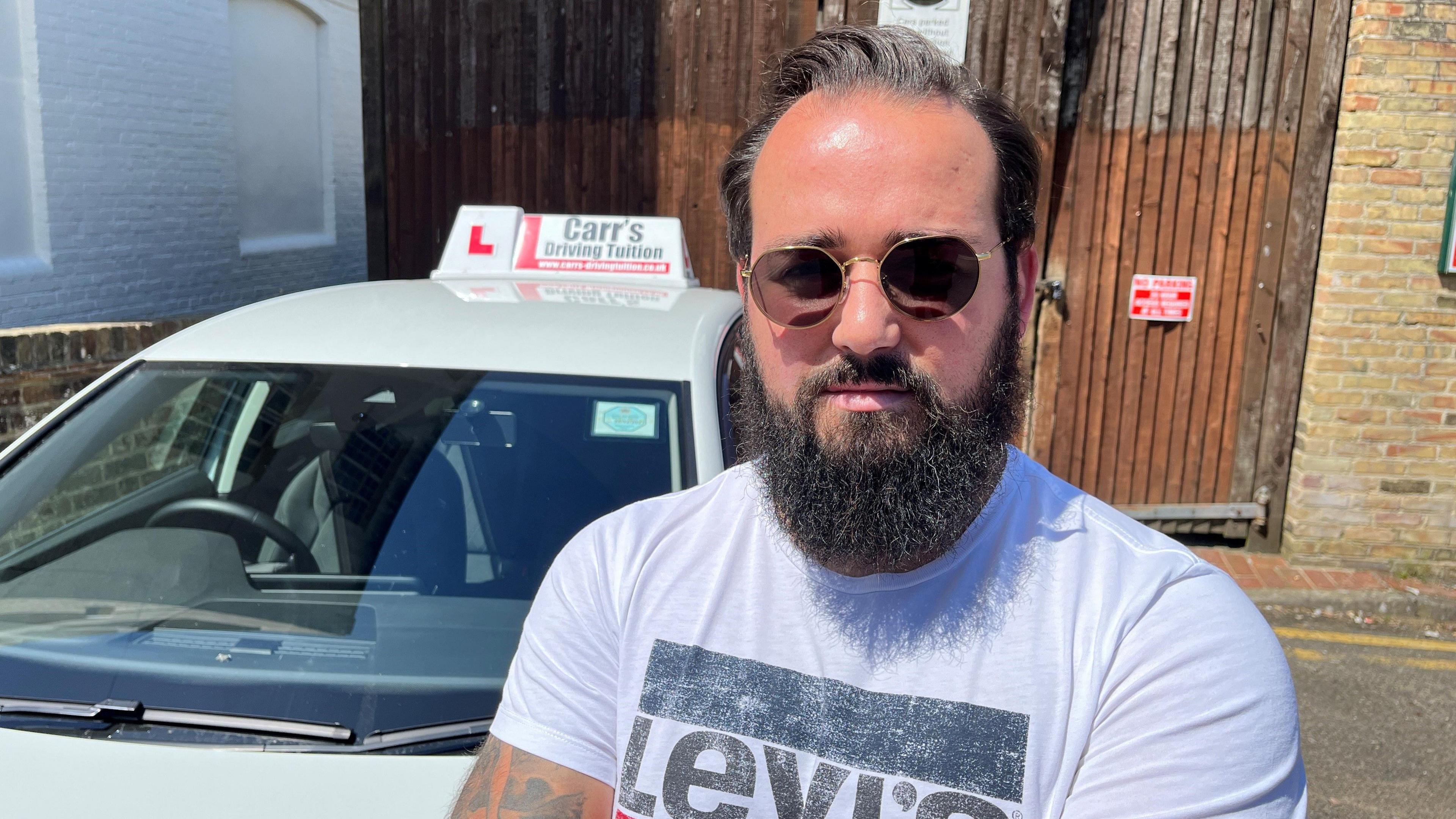 Francisco, a driving instructor standing by his car