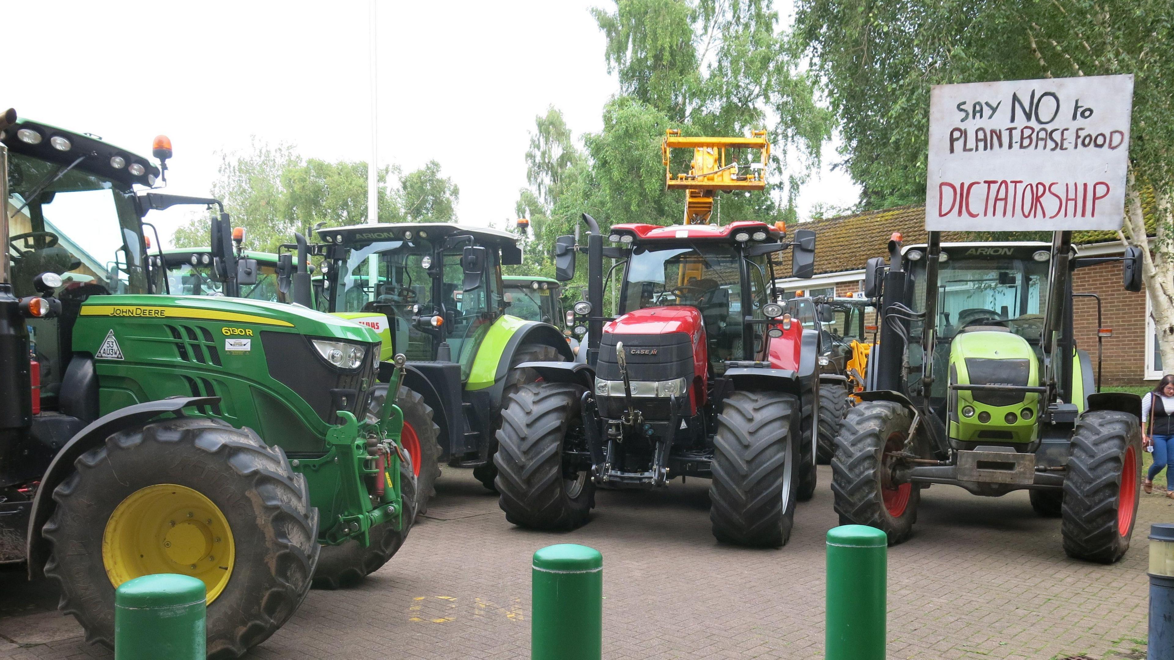 Tractors parked, with one bearing a sign that erads "say no to plant-base food dictatorship"