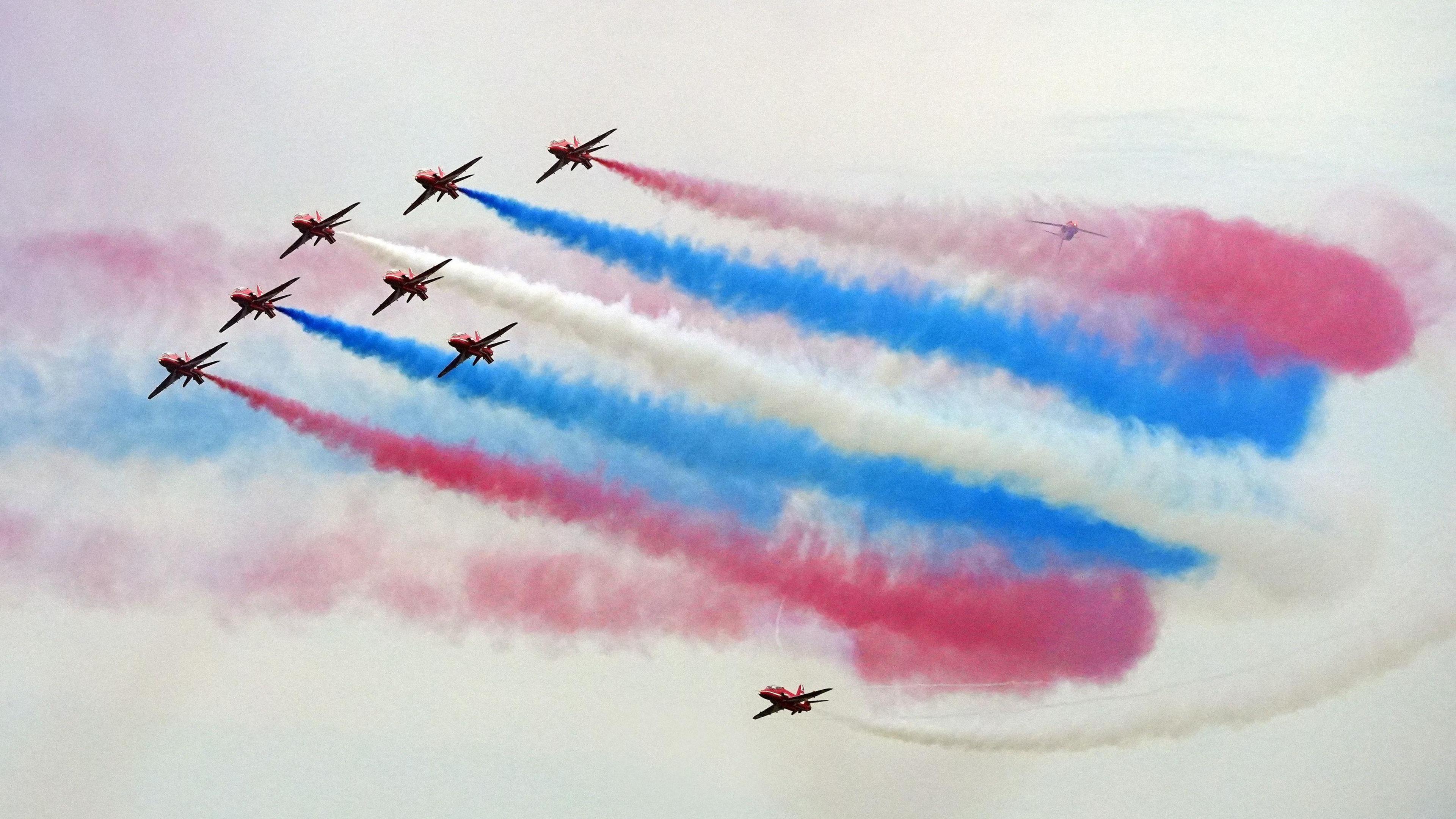 red arrows flying with smoke trails of red white and blue behind them.