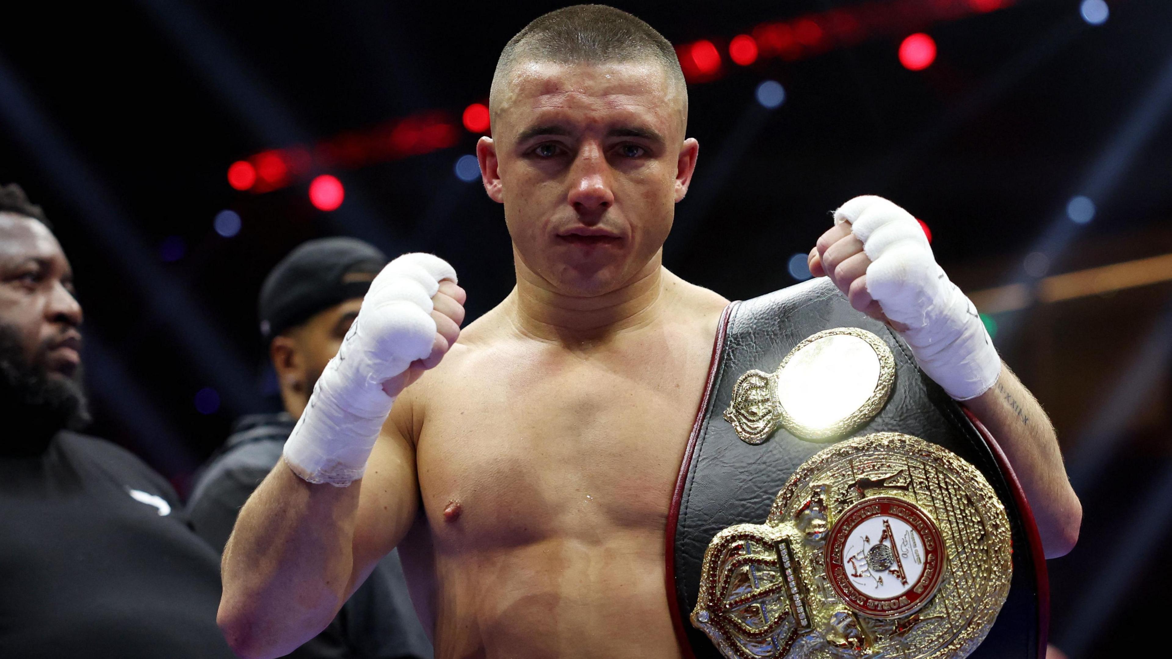 Nick Ball puts his fist up holding his WBA title