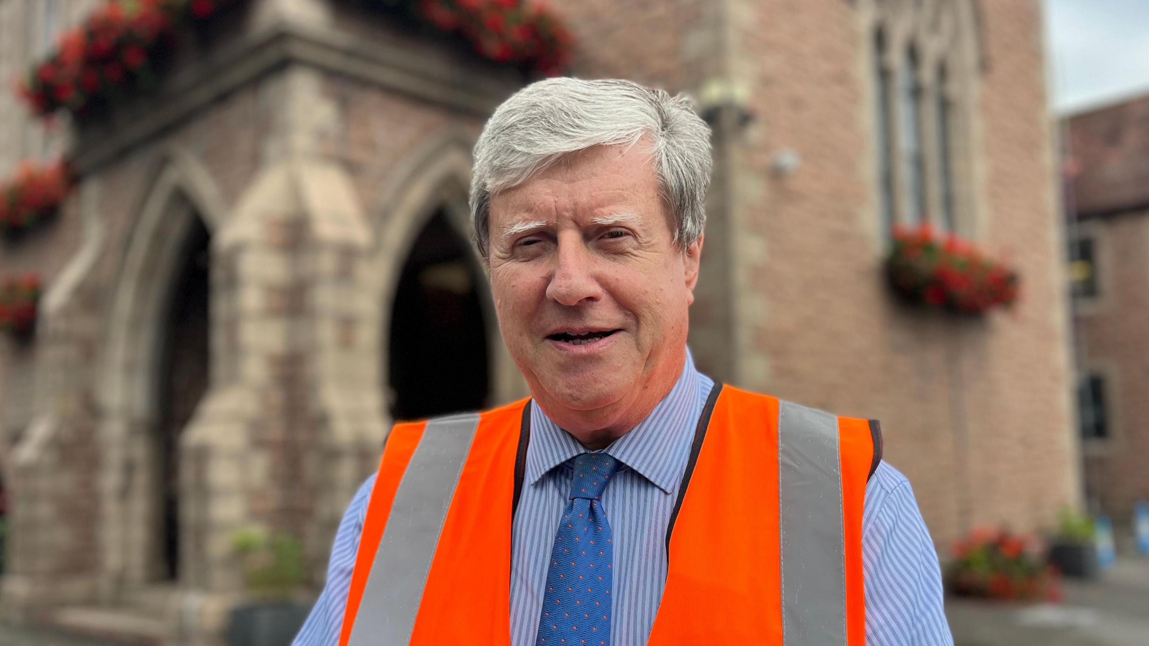 Constable Kevin Lewis stood in front of St Saviour's parish hall wearing an orange high-viz jacket.
