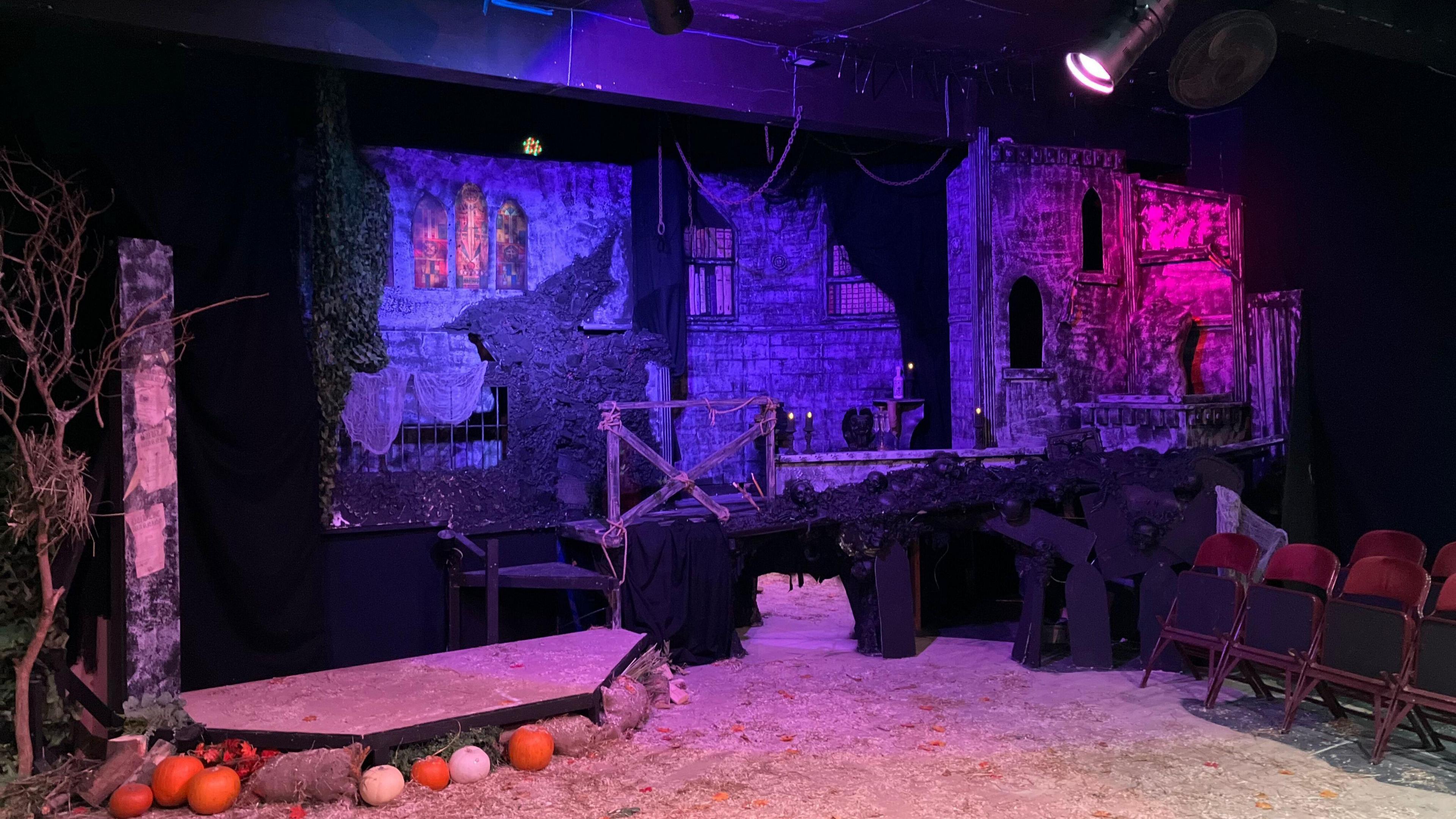 A stage space that is rigged up with lights and chairs. The stage is set up to resemble parts of Whitby to reflect the production of dracula.