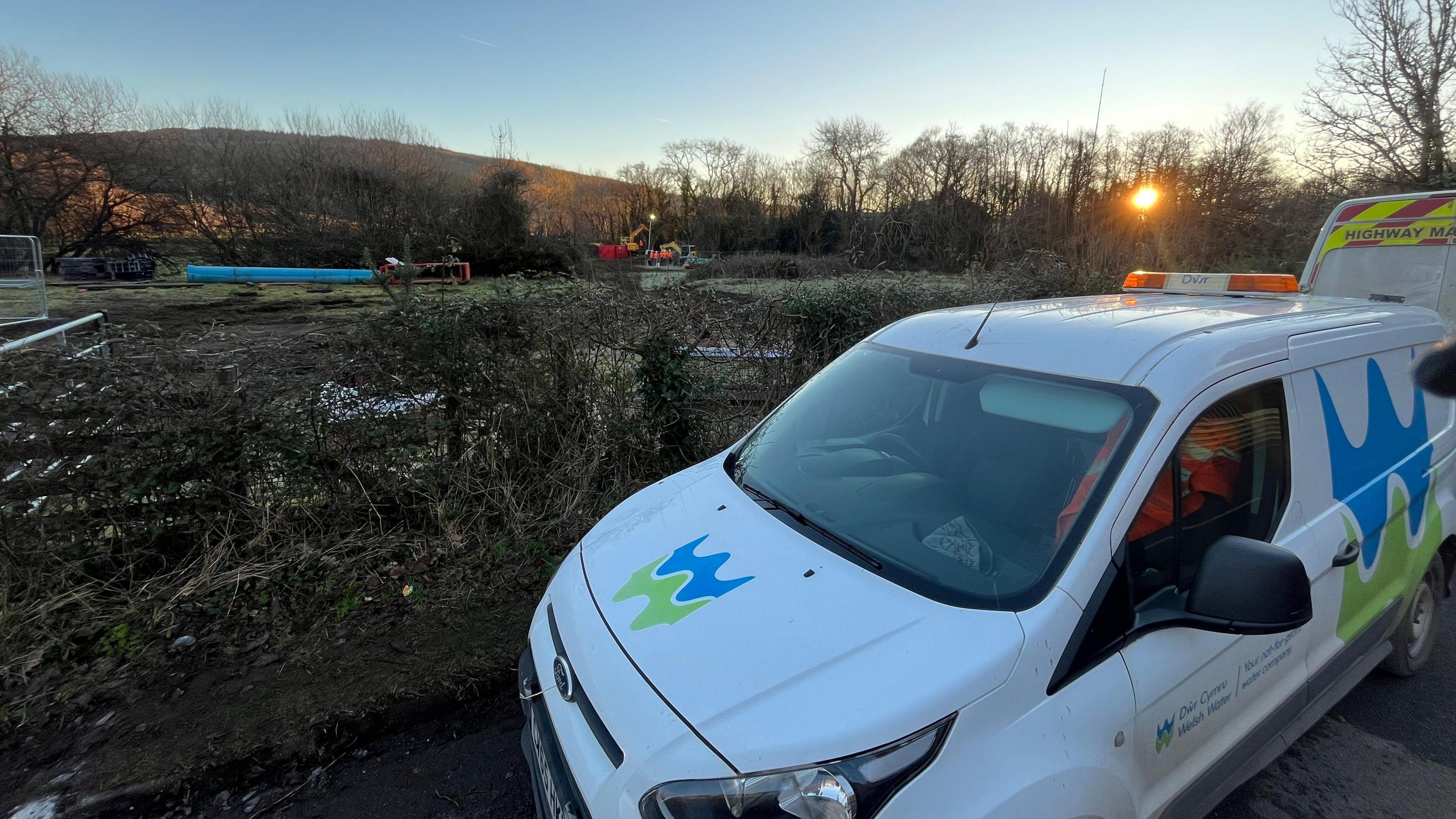 A van with the Welsh Water logo is parked outside building works on a field.