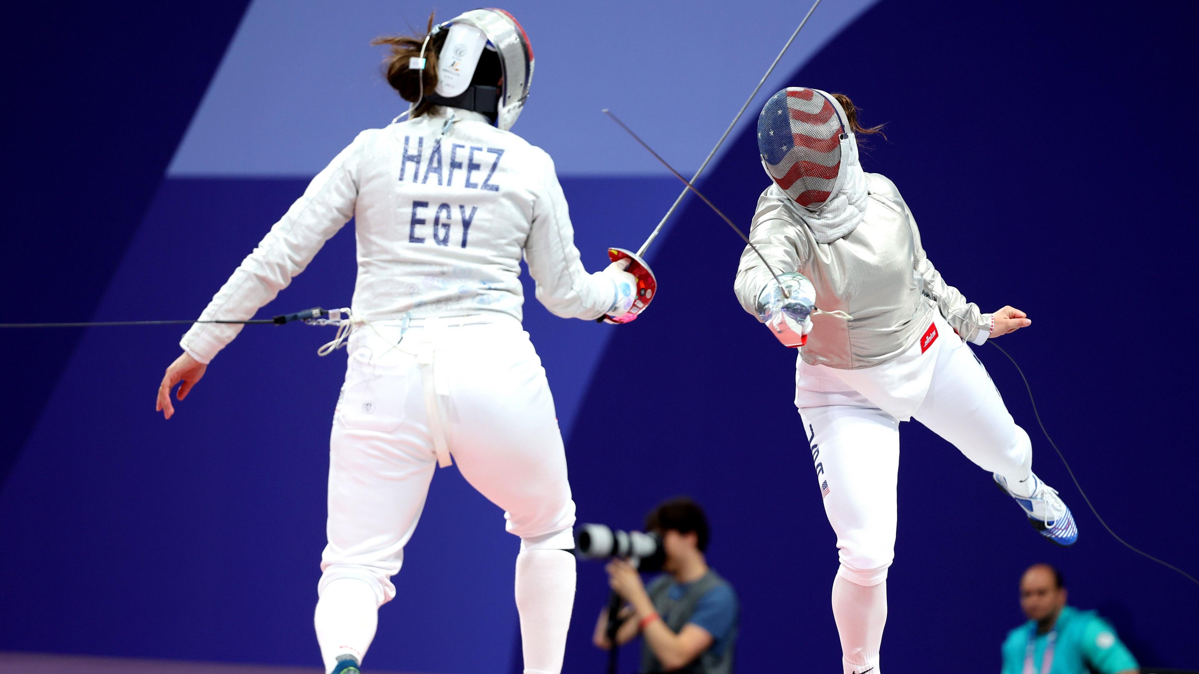 Nada Hafez of Egypt (left) is seen from behind as she clashes sabre swords with Elizabeth Tartakovsky of USA (right) in a fencing match at the Paris 2024 Olympic Games