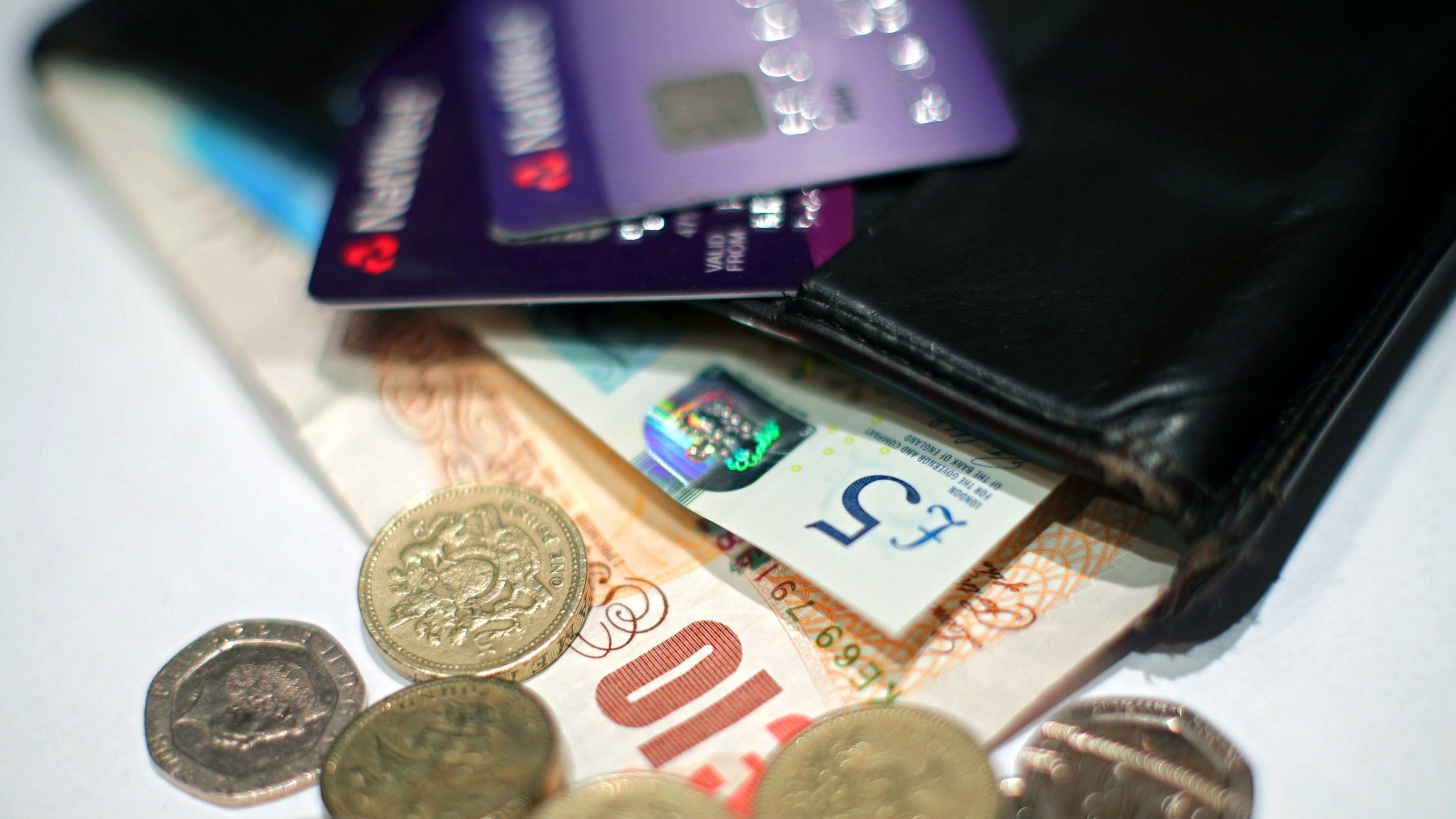 A stock picture of some money in a black wallet with some debit cards