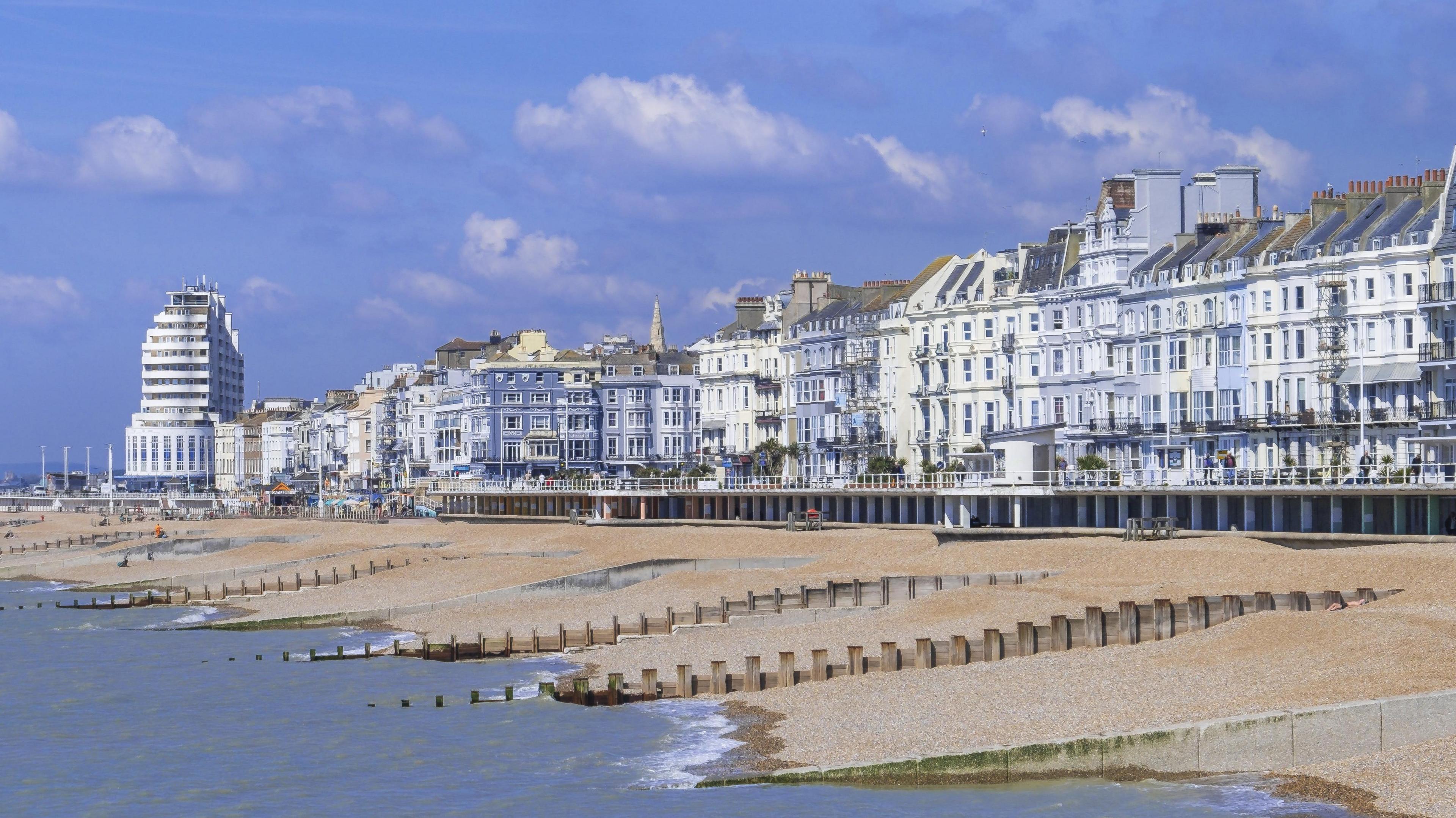 A picture of Hastings seafront. There is a line of Victorian homes with the shingle beach and water in front of them.