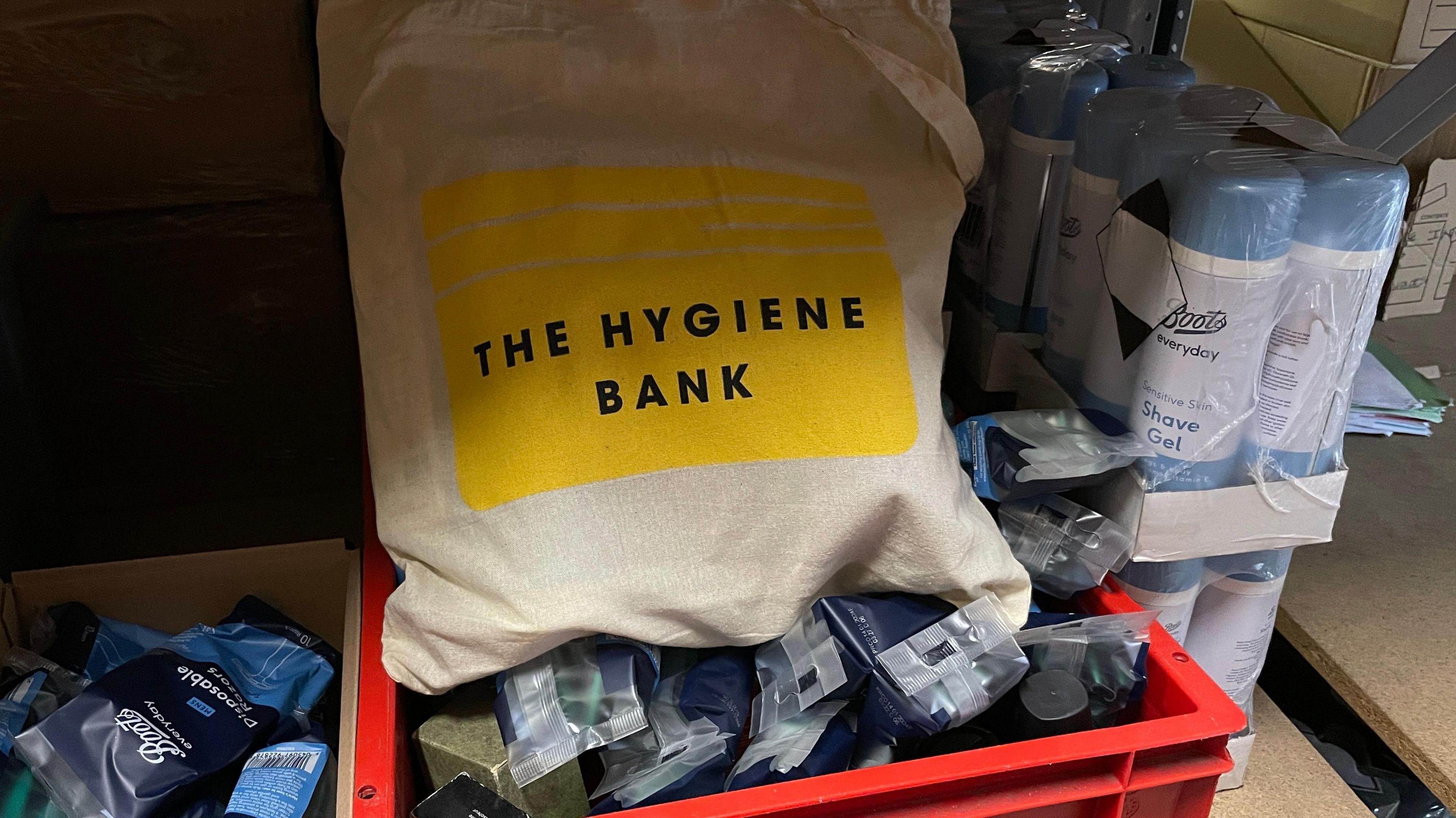 A bag from the hygiene bank containing donations of toiletries. There is also a box of shaving gel to the right of the bag.