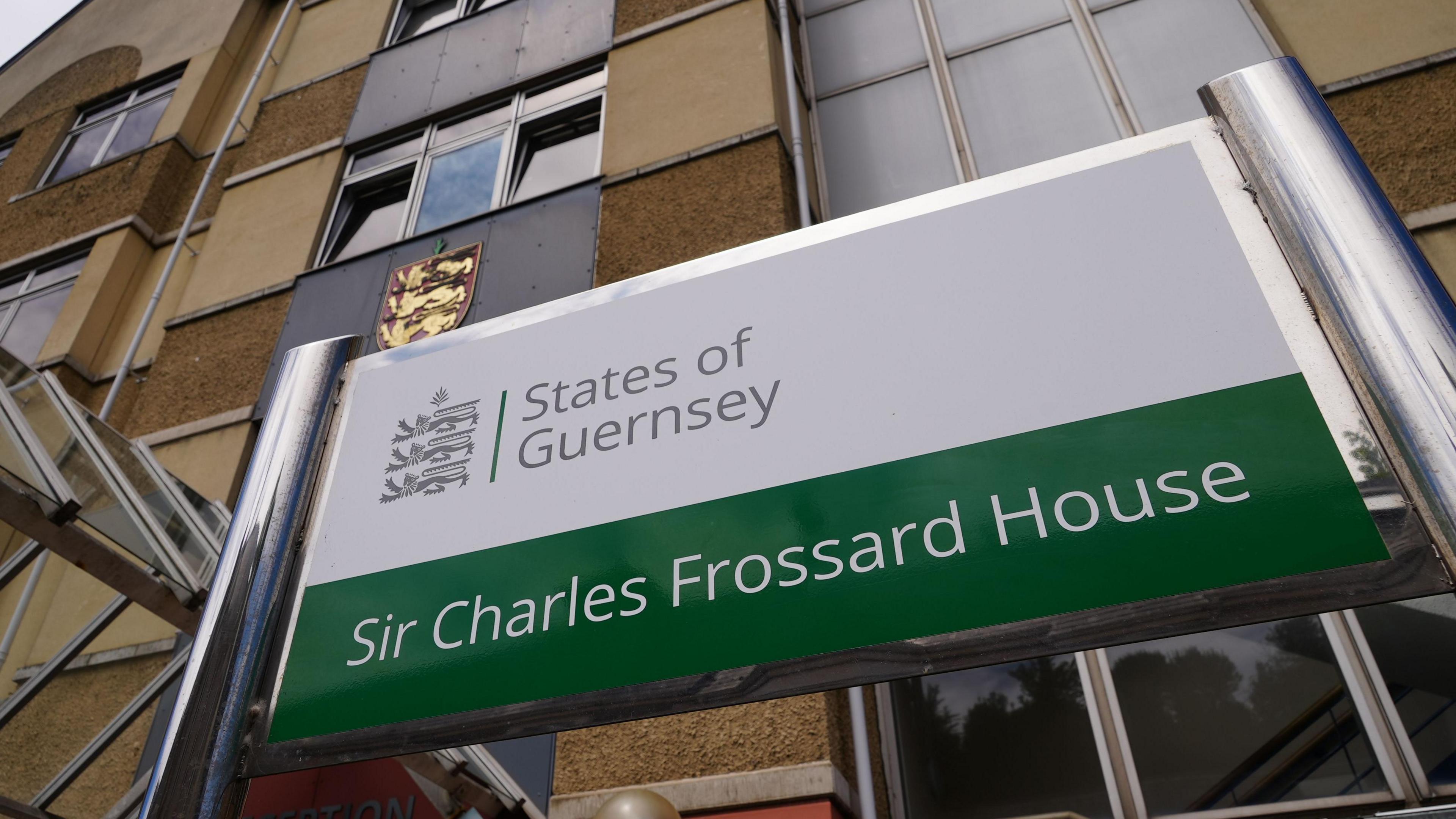 The front of Sir Charles Frossard House in Guernsey with a large green and white sign with the building's name and States of Guernsey written on it.