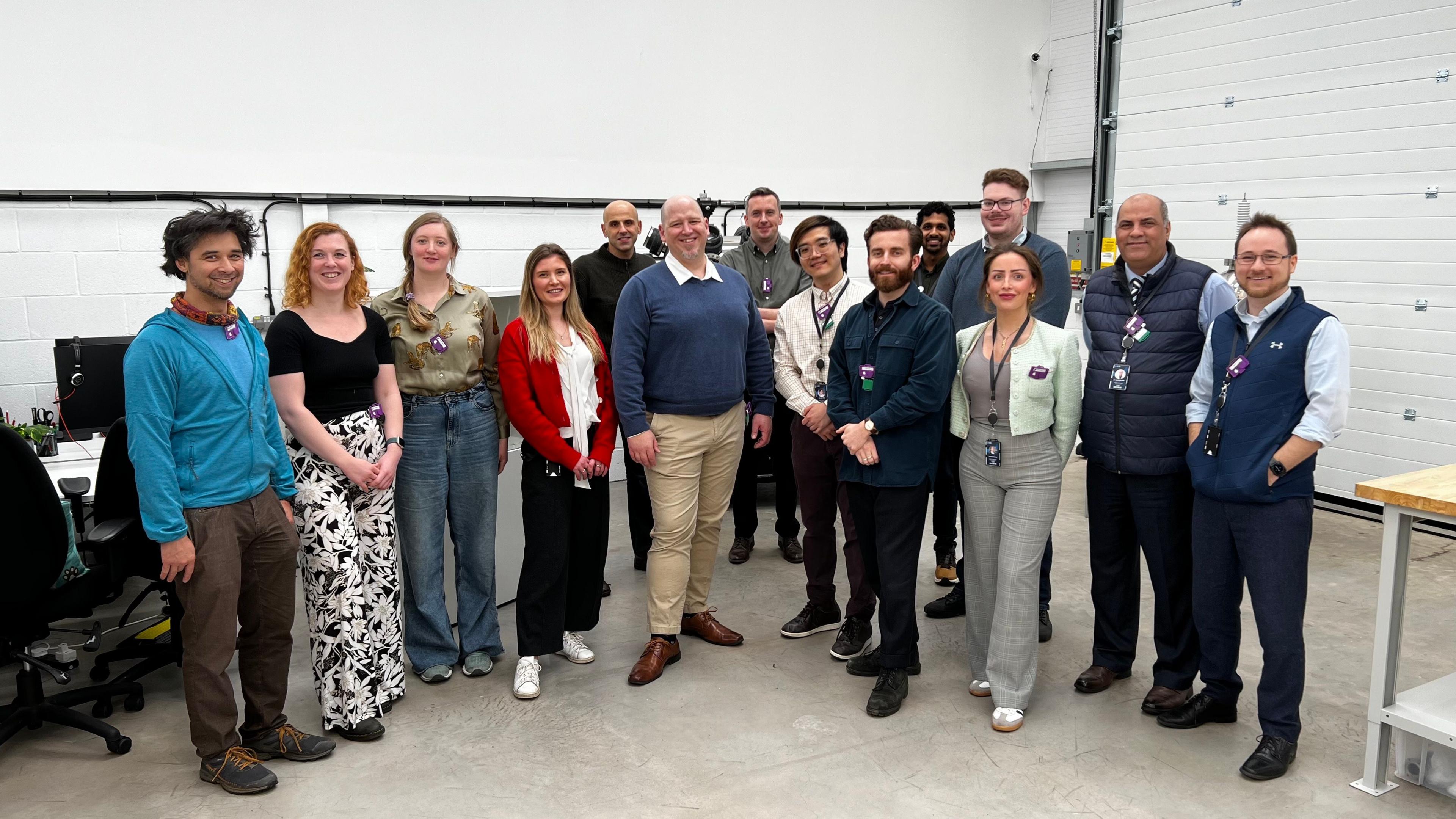 Members of staff at Astral Systems line-up for a photo in the lab. There are 14 people, of a range of ages and gender.