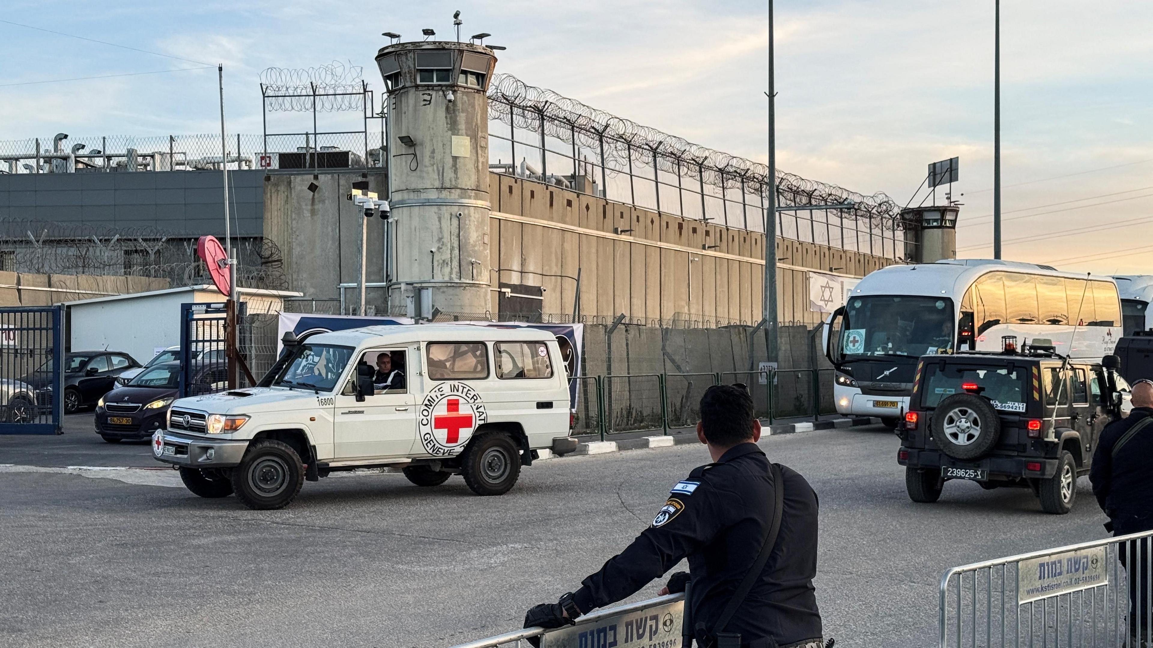 Israeli security forces watch as a Red Cross vehicle and a coach wait outside Ofer prison in the occupied West Bank (19 January 2025)