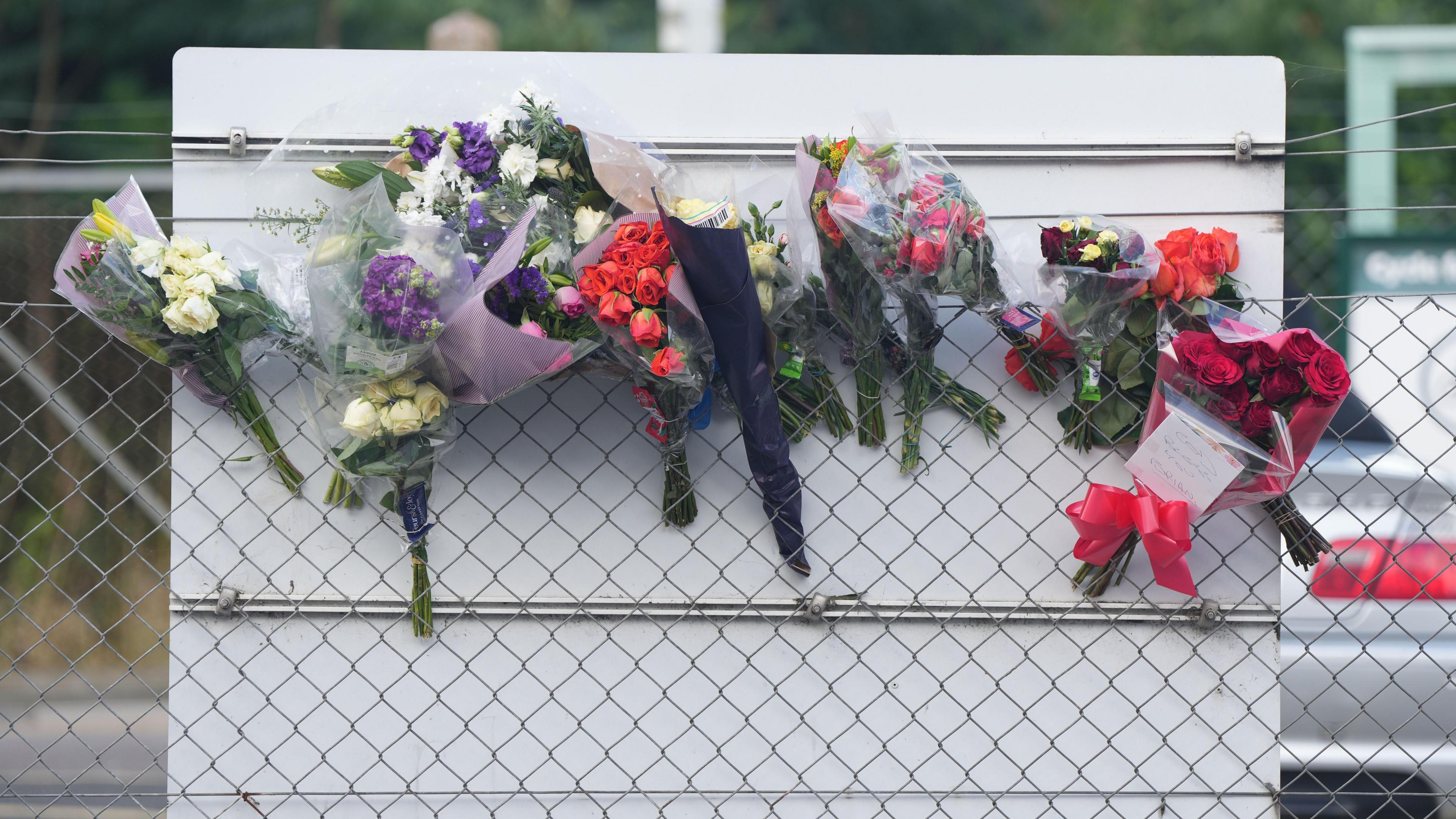 Close up of various bouquets of flowers attached to a fence.