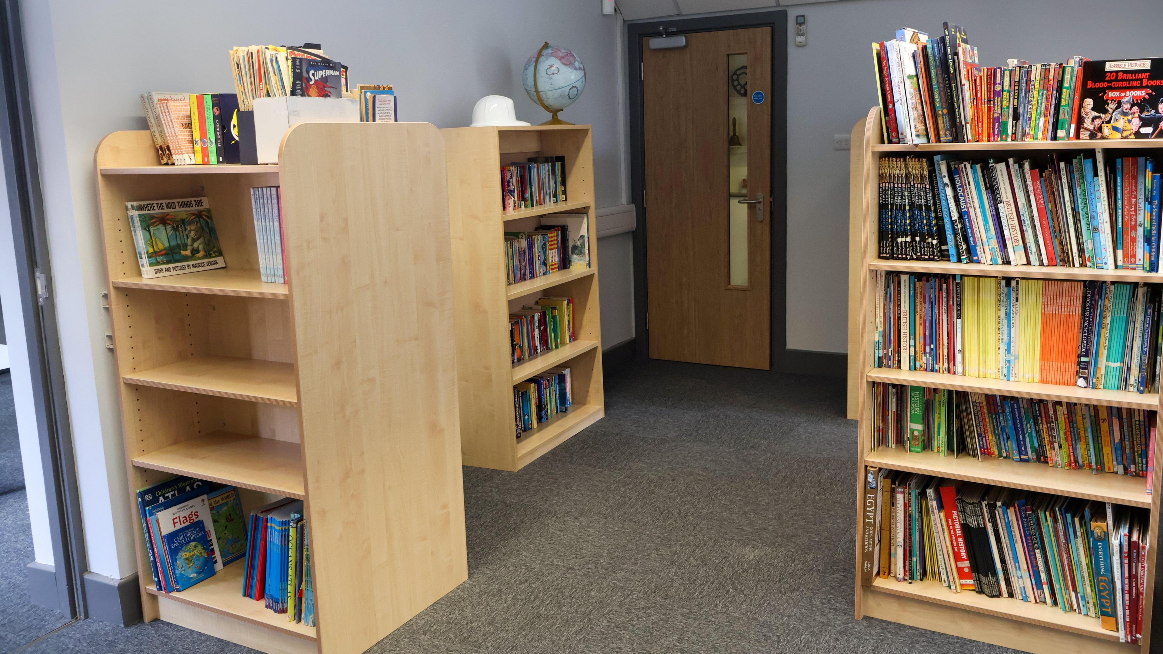 Light wood bookcases with colourful books inside.