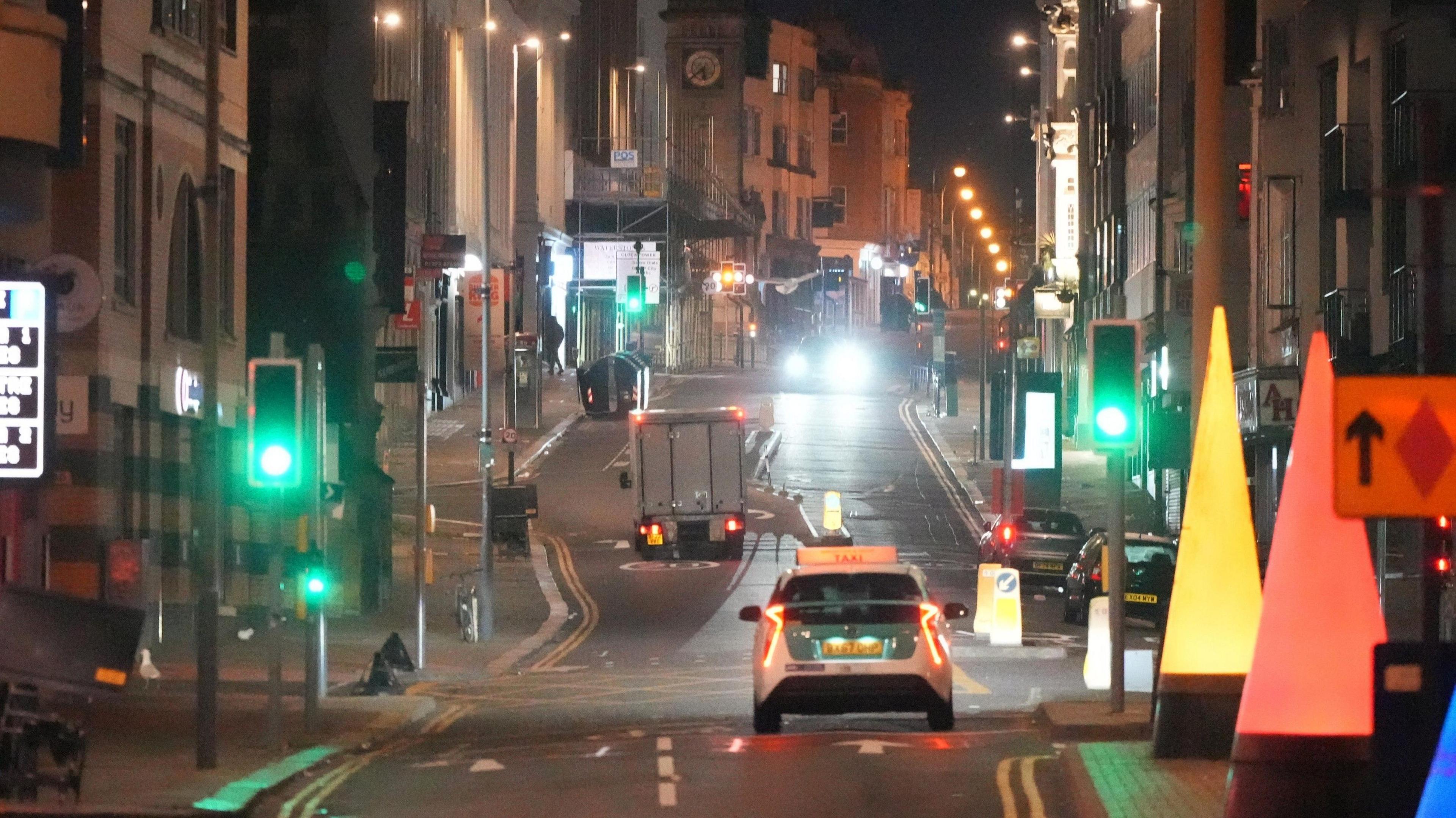 A single taxi drives down West Street in Brighton in the early hours of the morning.