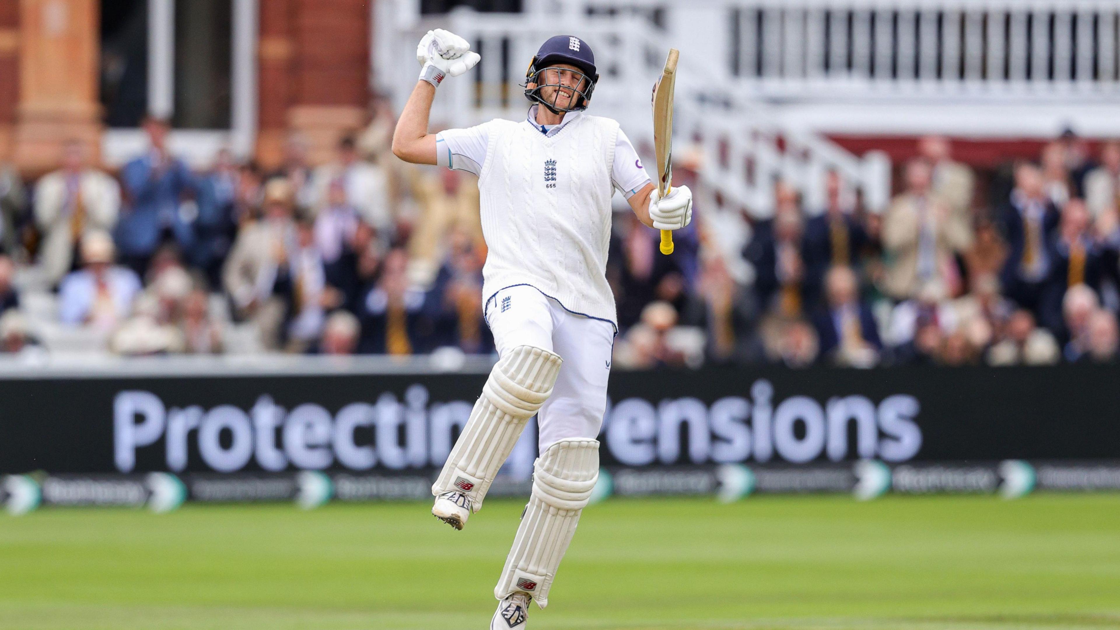 Joe Root jumps up in celebration holding his cricket bat