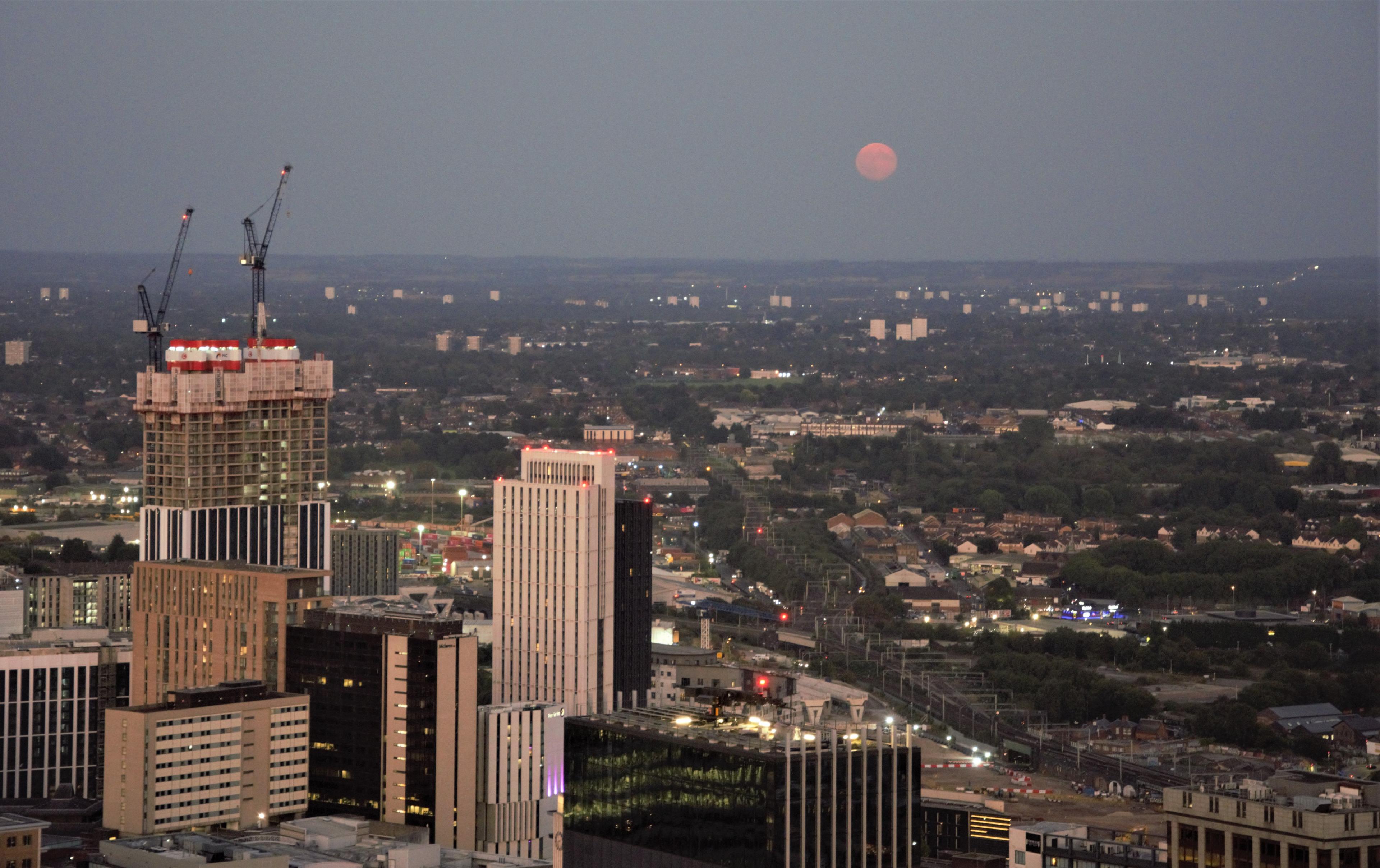 Birmingham skyline below a pink moon