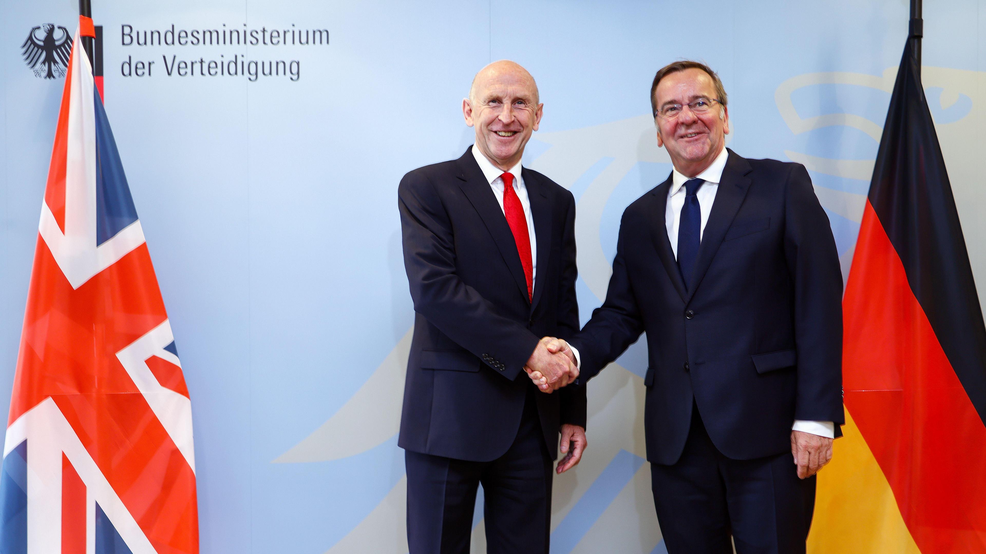 German Defence Minister Boris Pistorius and UK Defence Secretary John Healey shake hands in front of UK and German flags