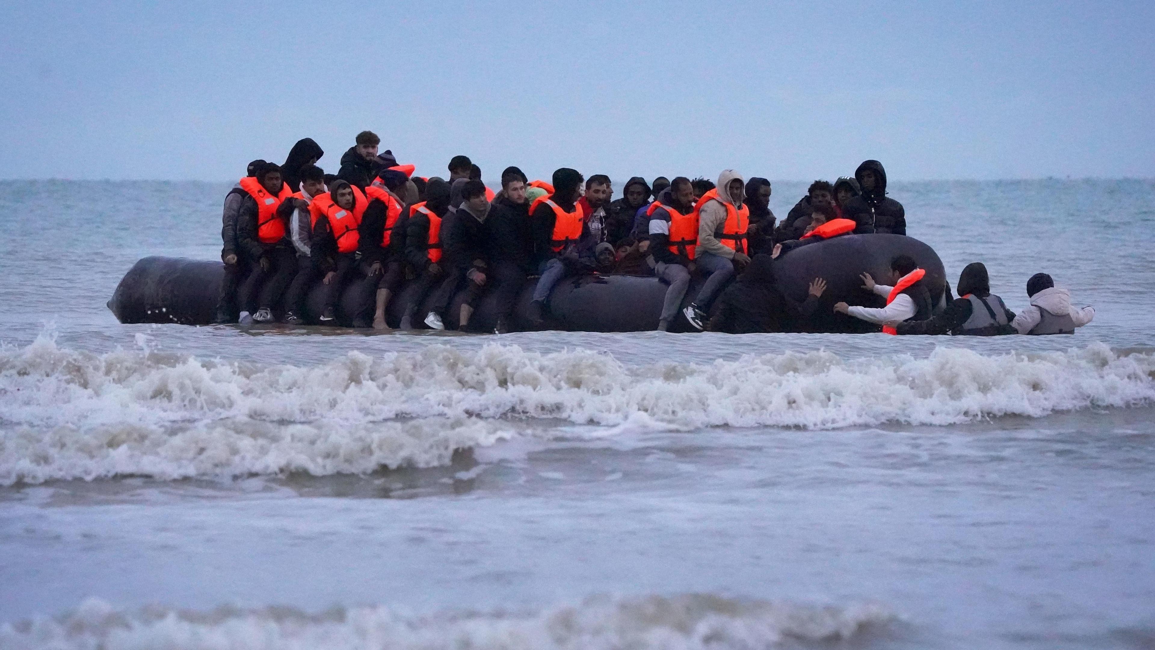 People thought to be migrants wade through the sea to board a small boat in Gravelines, France.