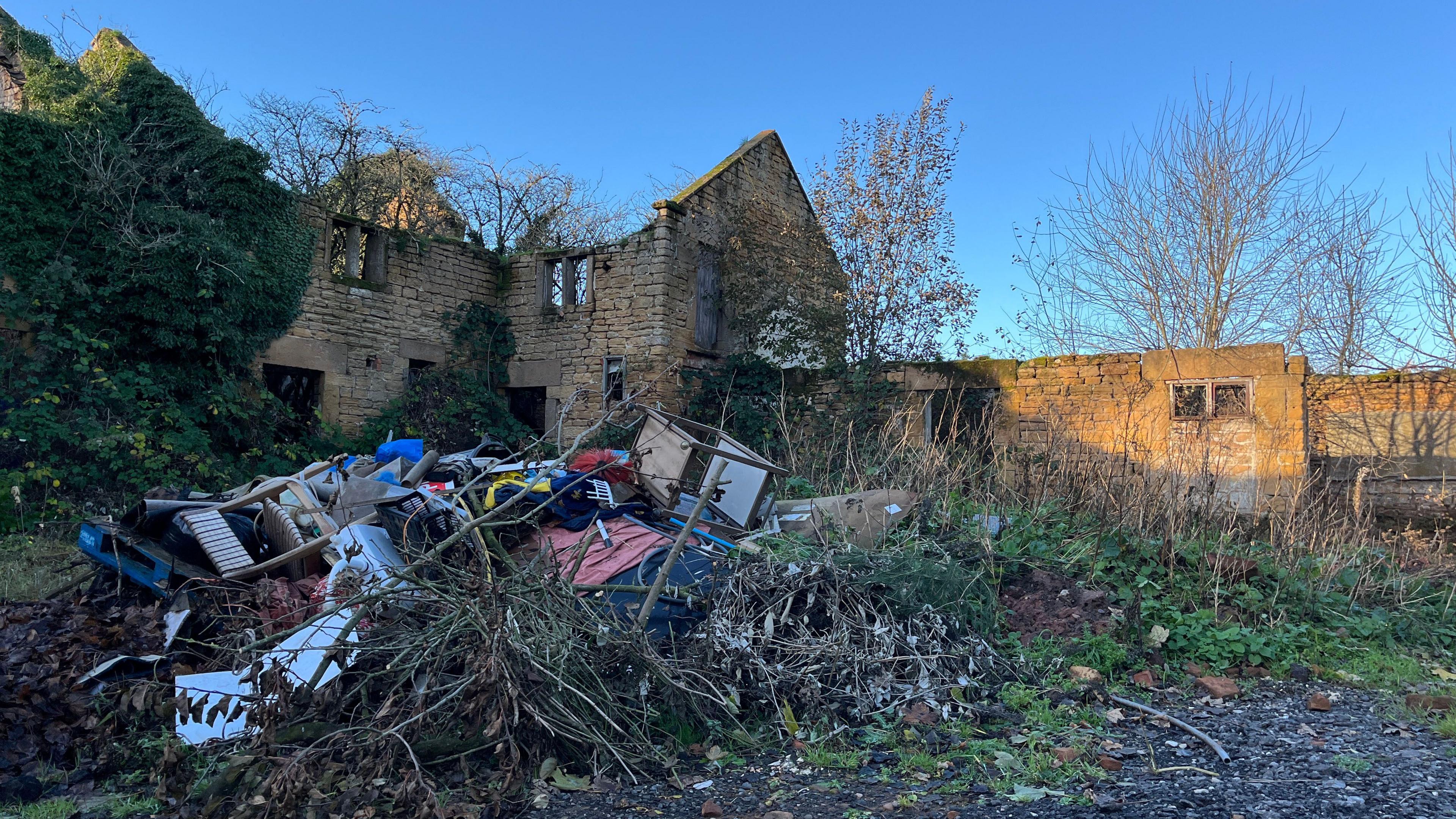 Rubbish including chairs and pallets left next to a ruined house