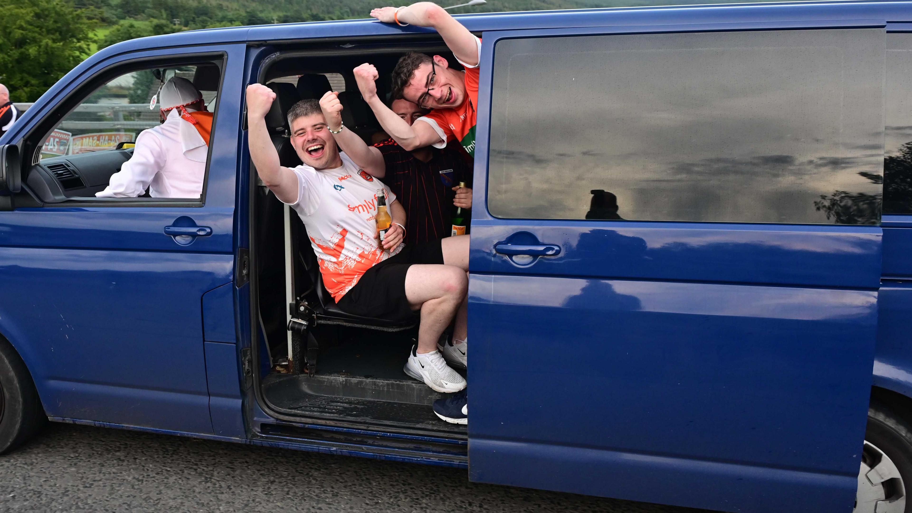 Fans hanging out of a blue van