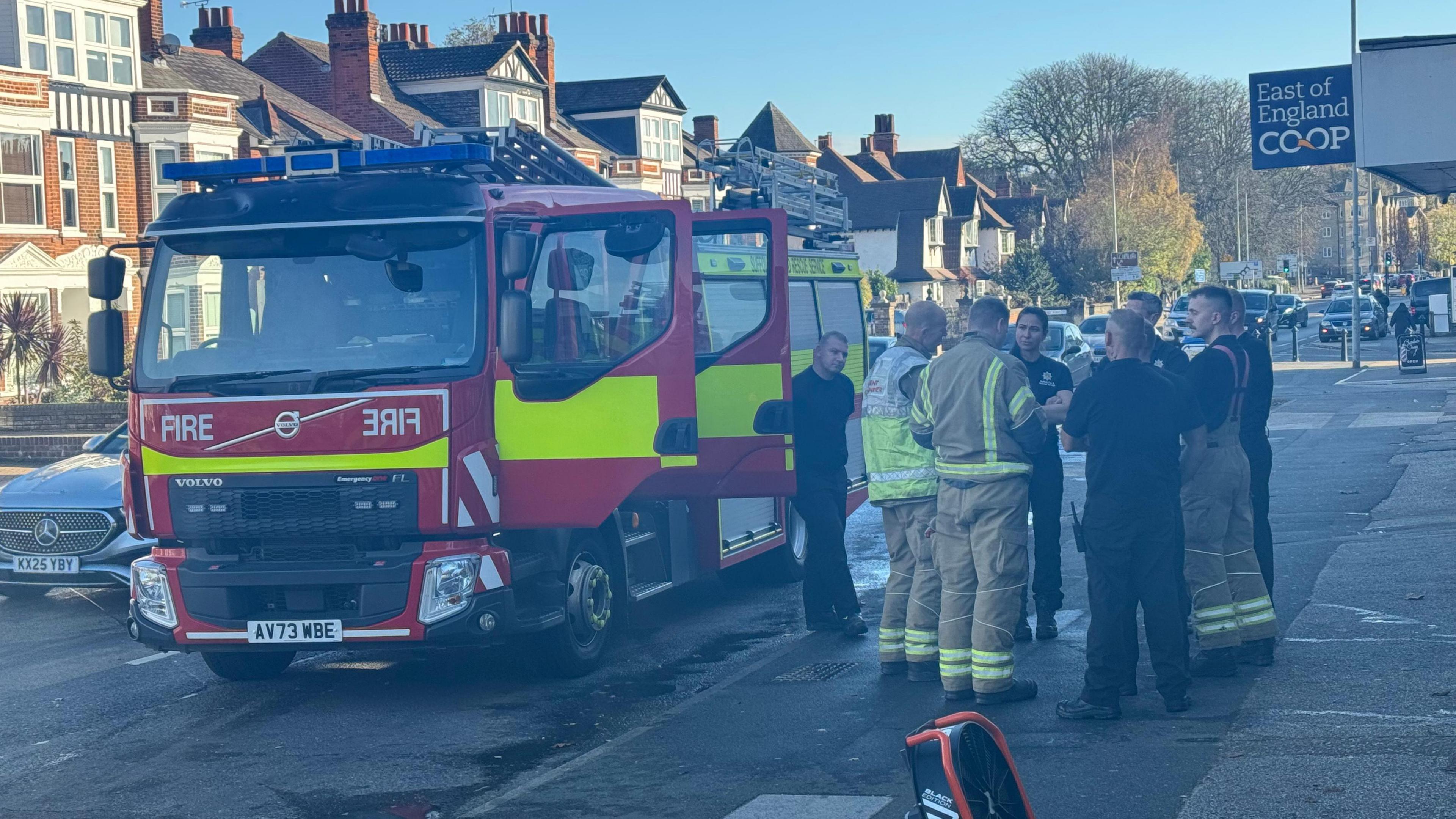 A group of firefighters talking while standing next to a fire engine on Norwich Road in Ipswich. 