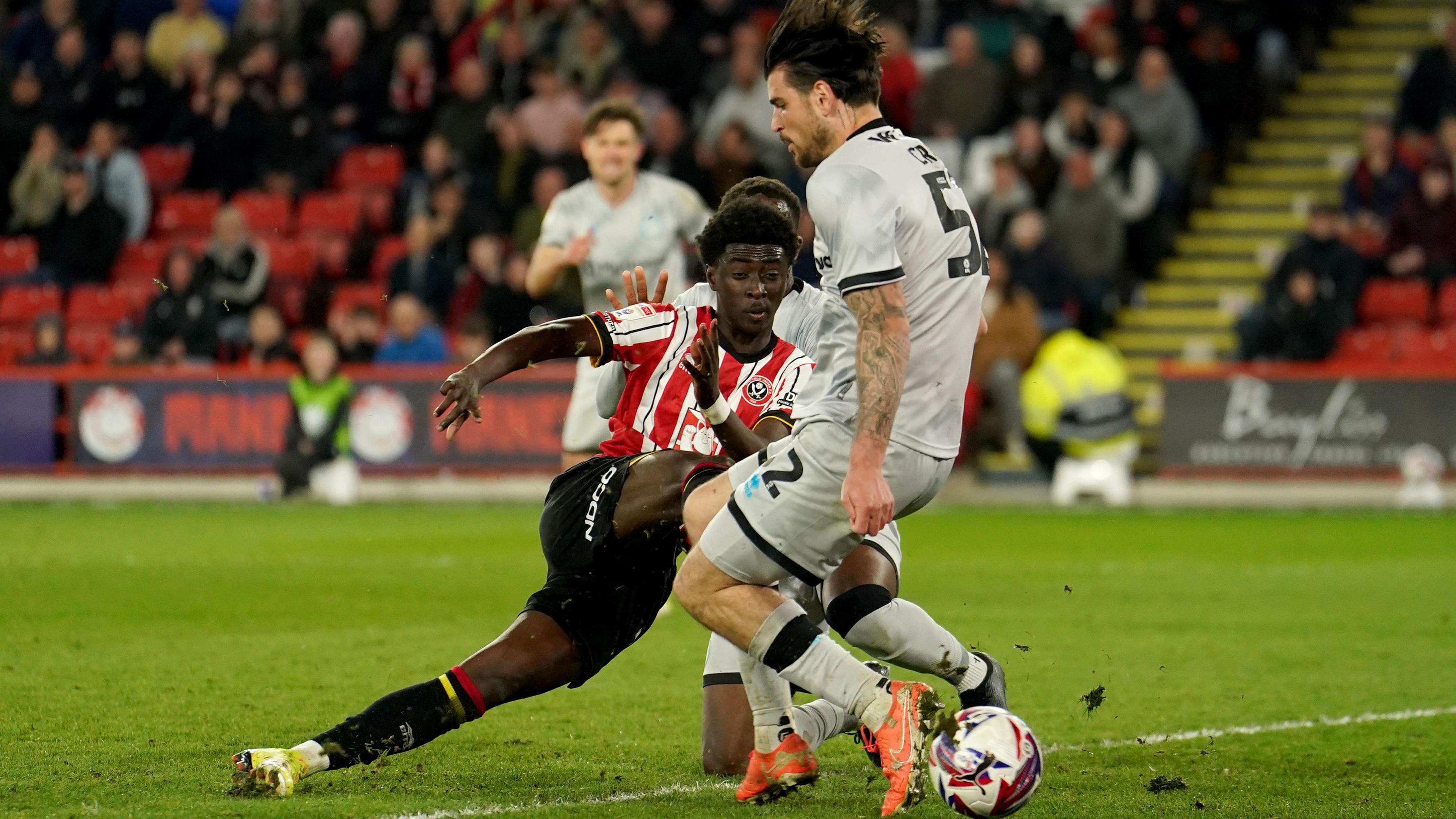 Jesurun Rak-Sakyi [left] drags a shot wide for Sheffield United while under pressure from Millwall's Tristan Crama [right]
