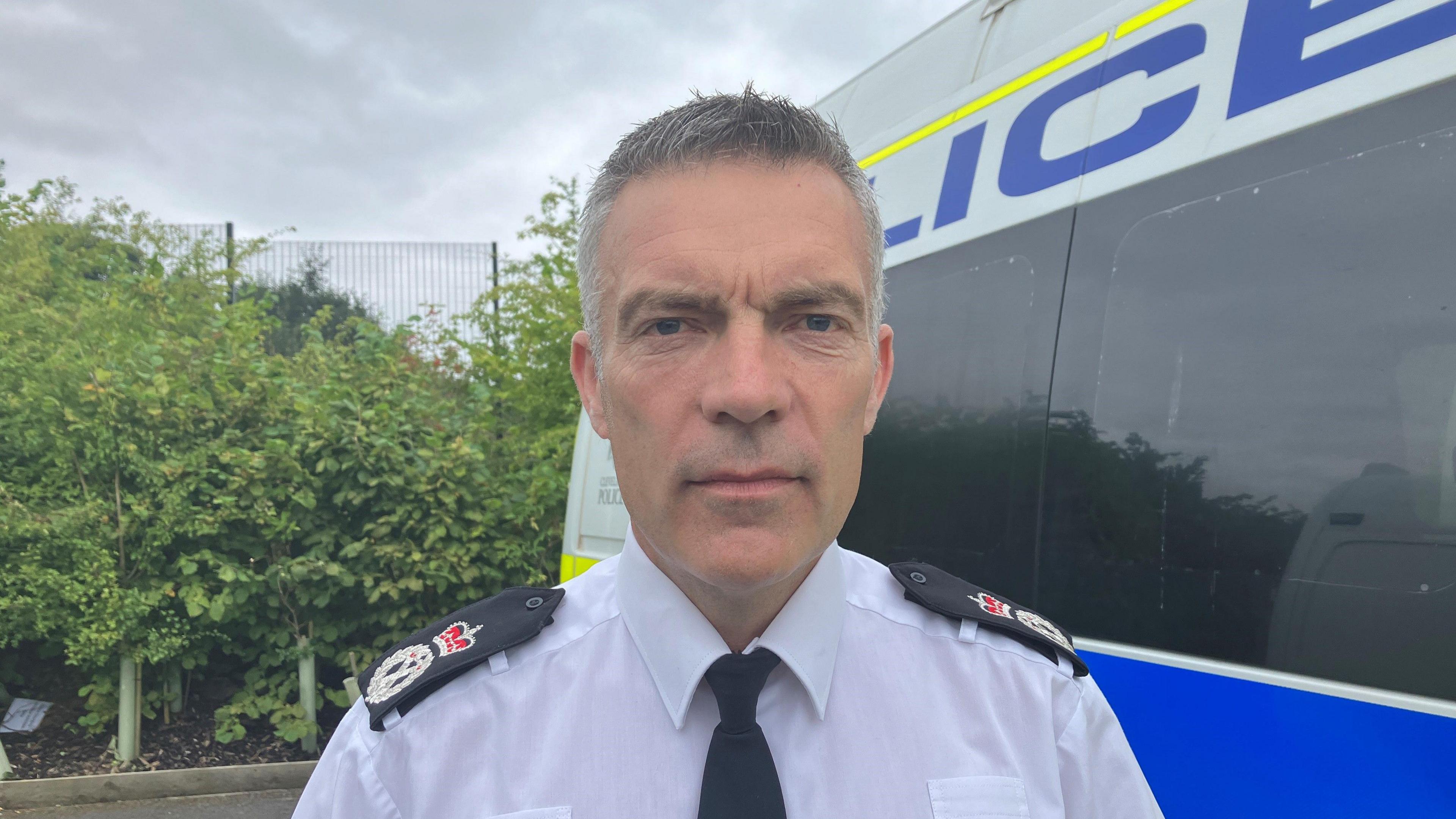 Chief Constable Mark Webster in uniform standing in front of a police van.