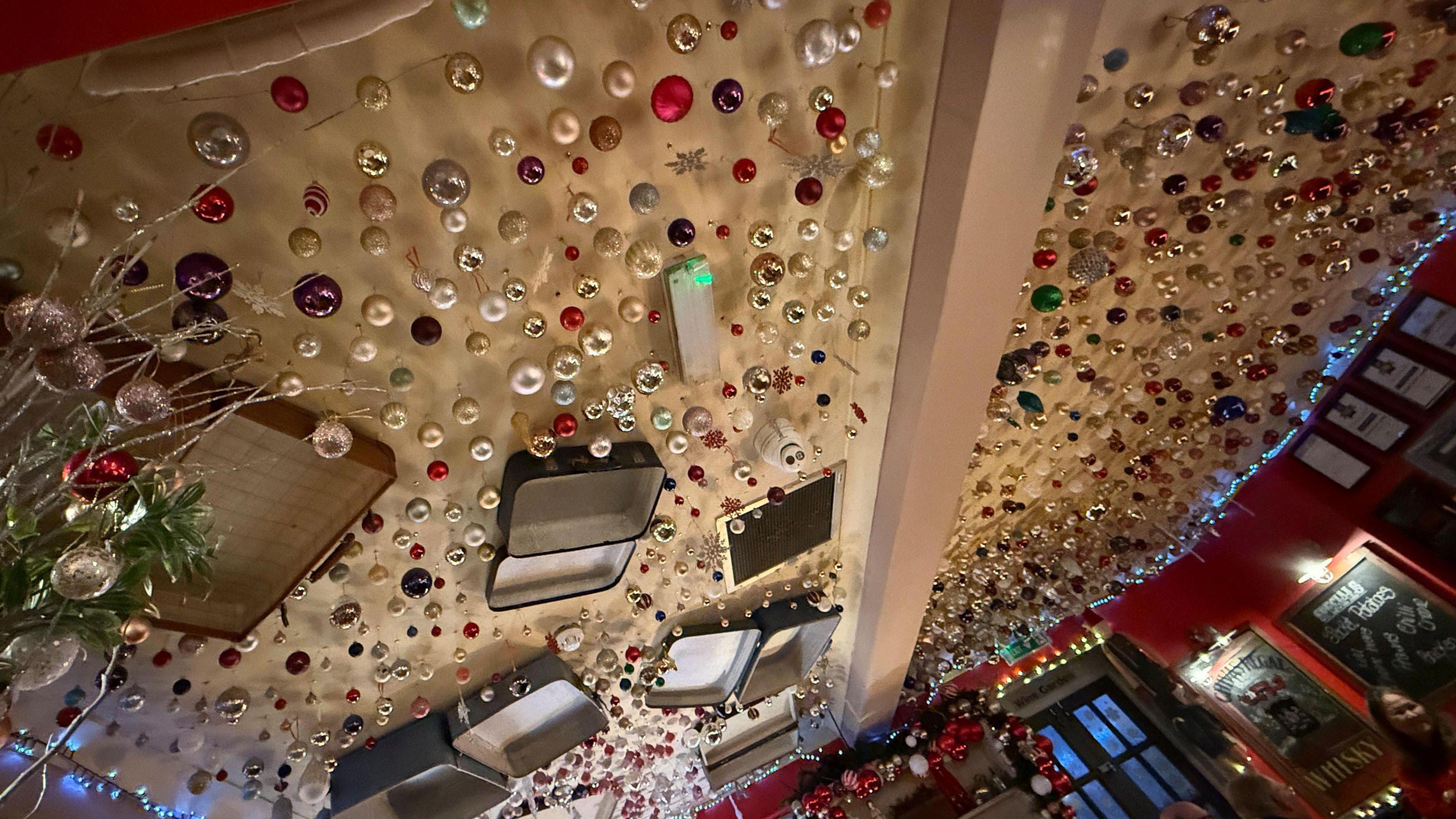 The ceiling of the pub is decorated with hundreds of baubles. It also is decorated with old open suitcases and a guitar.