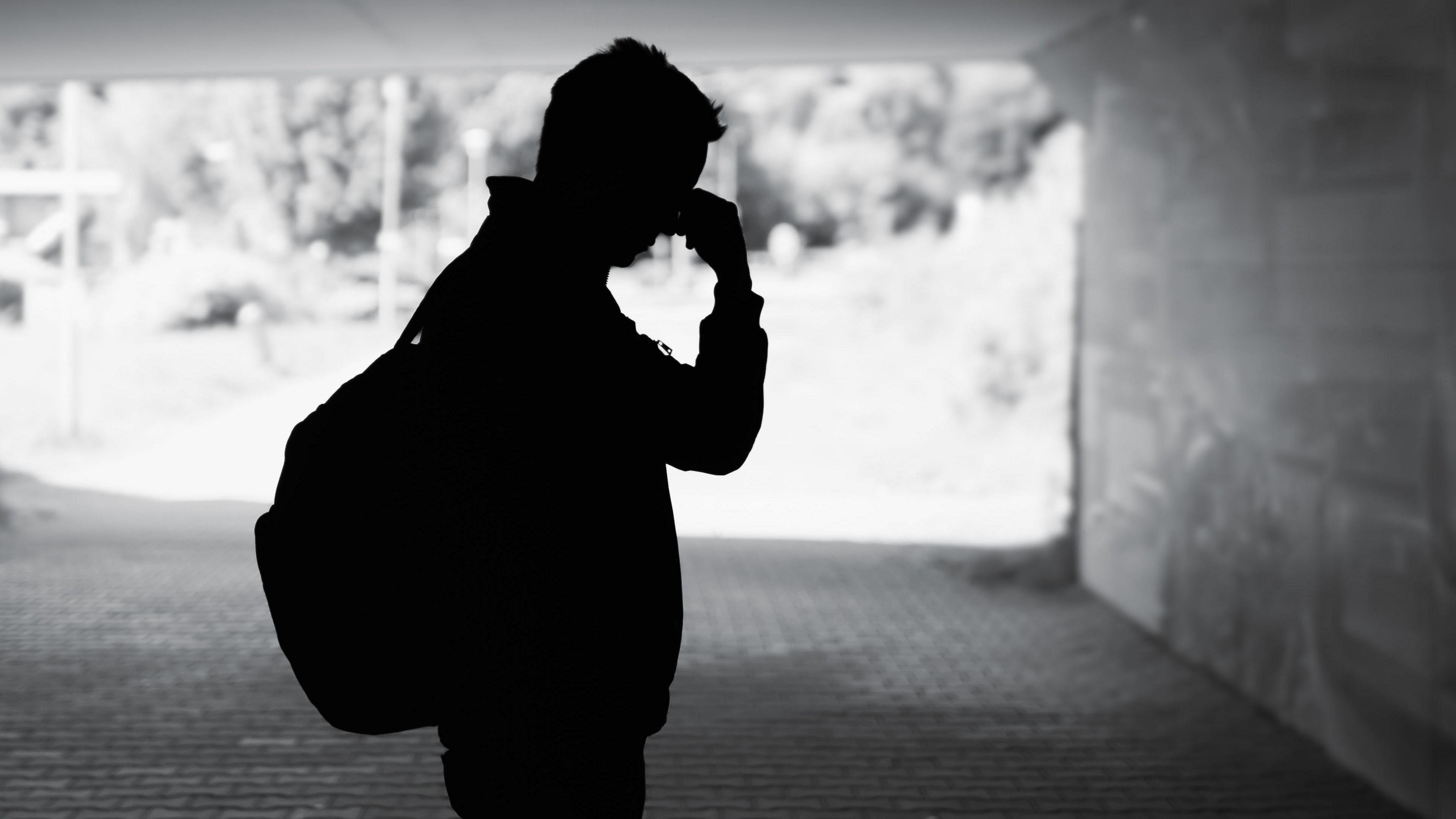Silhouette of a man in an underpass with his hand touching his forehead