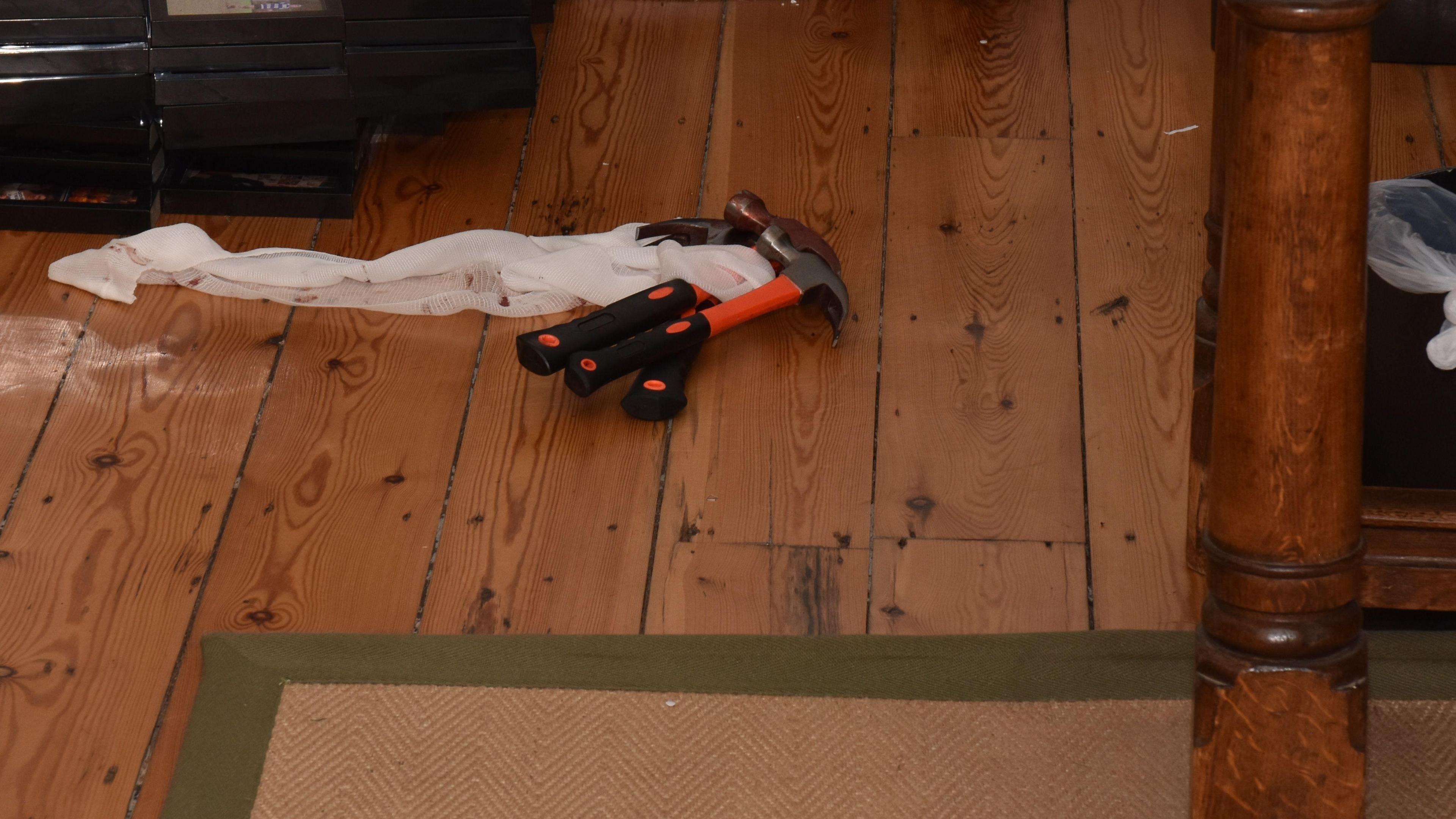 Three claw hammers with orange hammers on a wooden floor in a private school bedroom.