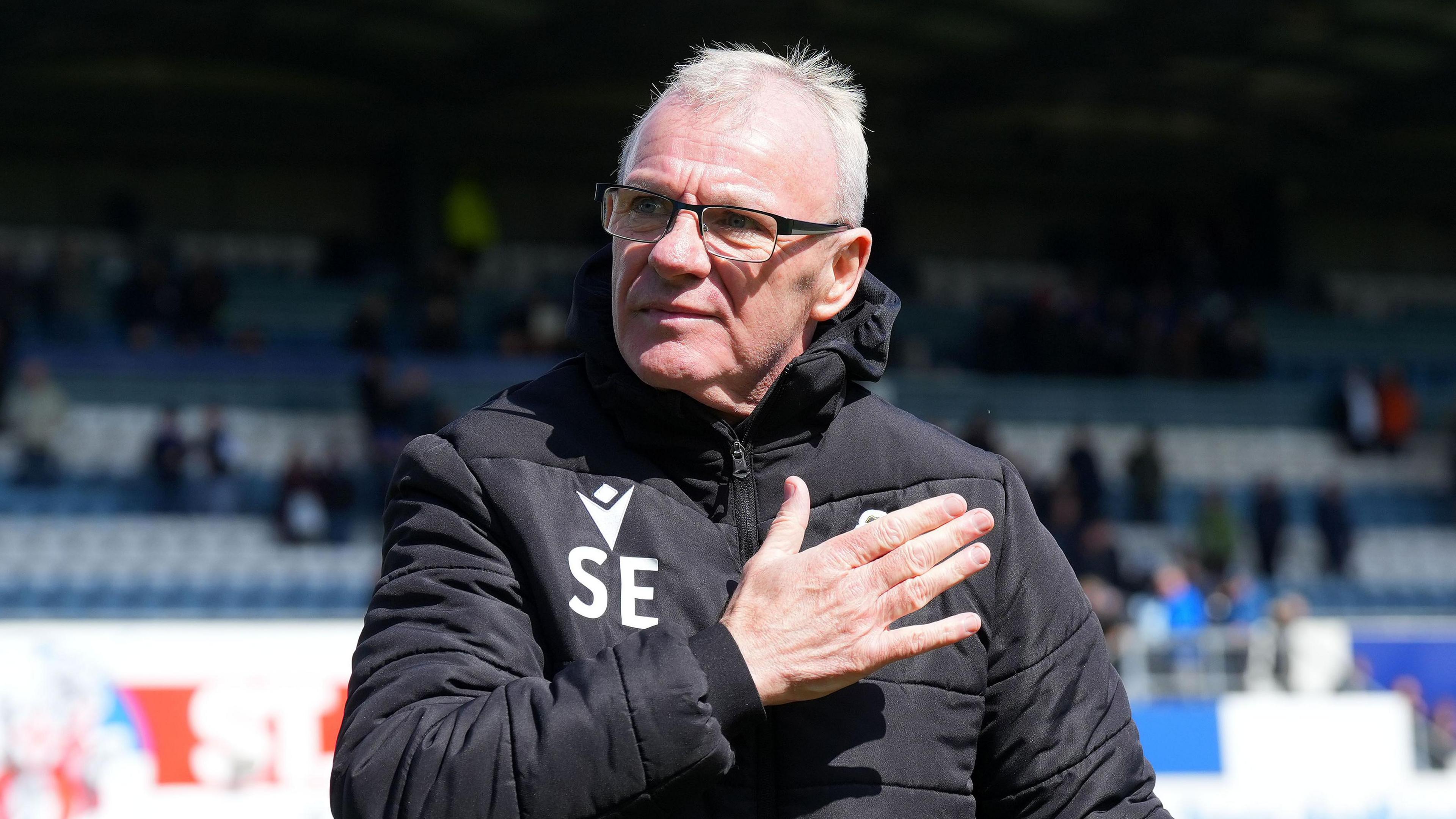 Steve Evans stands on the pitch at the Memorial Stadium at full-time of a match with his hand flat against his chest