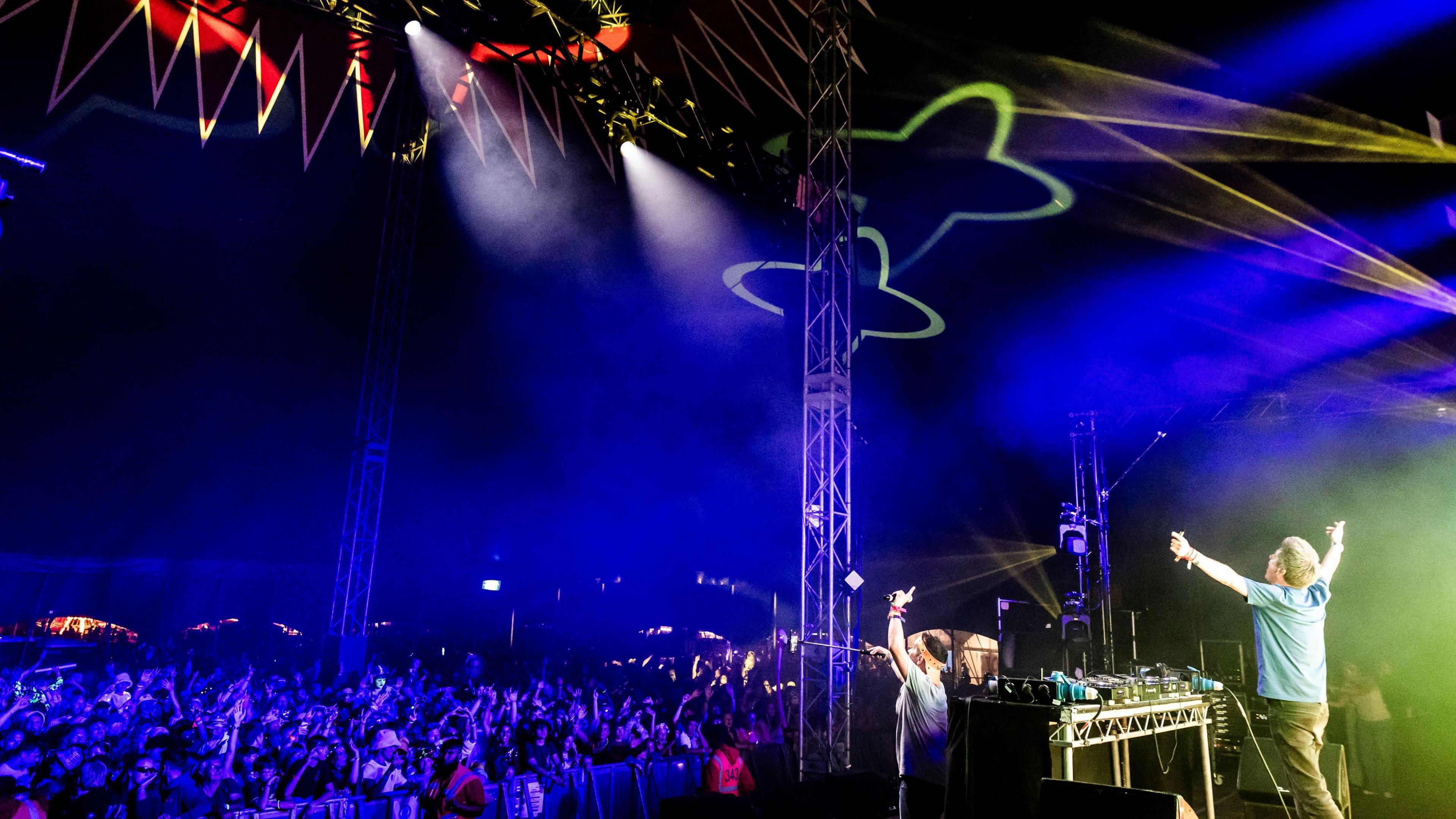 Dick and Dom perform on a stage in front of a crowd at Camp Bestival 